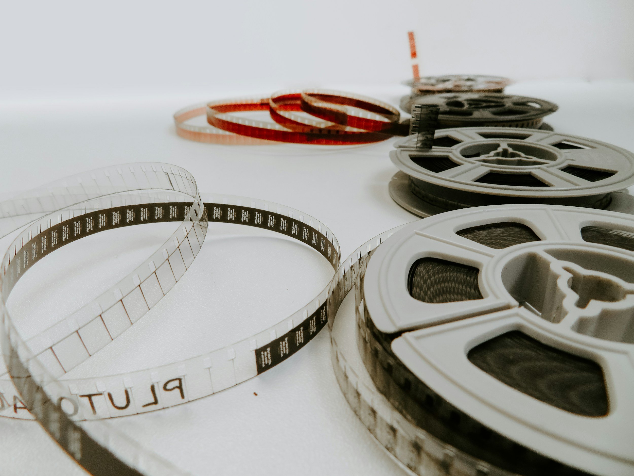 Spools of 16mm film, some white and some black, arranged in a row on a white surface.