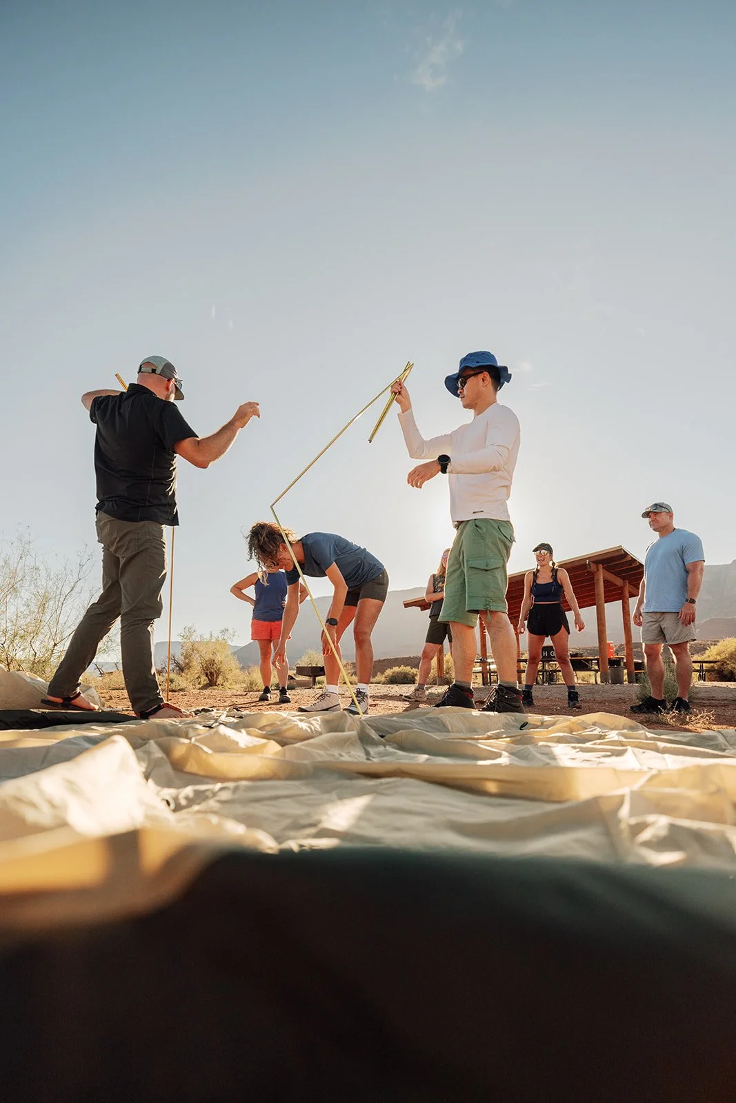 Group of people setting up a tent outdoors in a desert area.