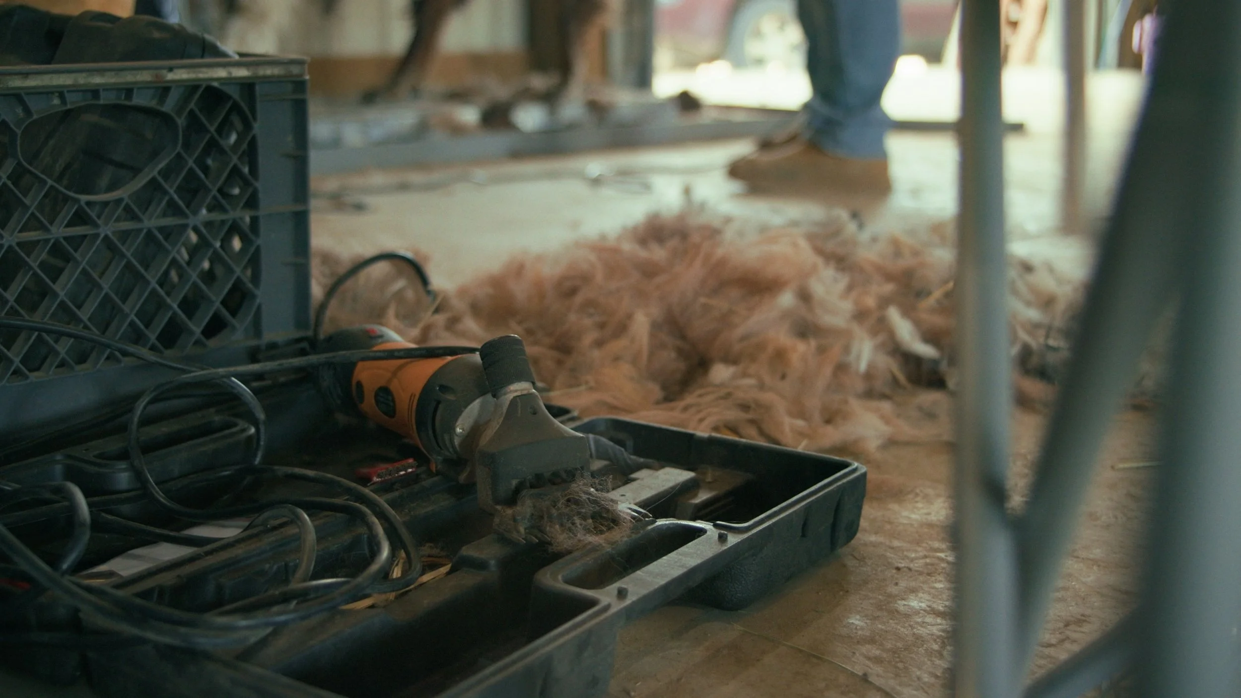 Tools and equipment in a workshop with a pile of fur or hair on the floor in the background.