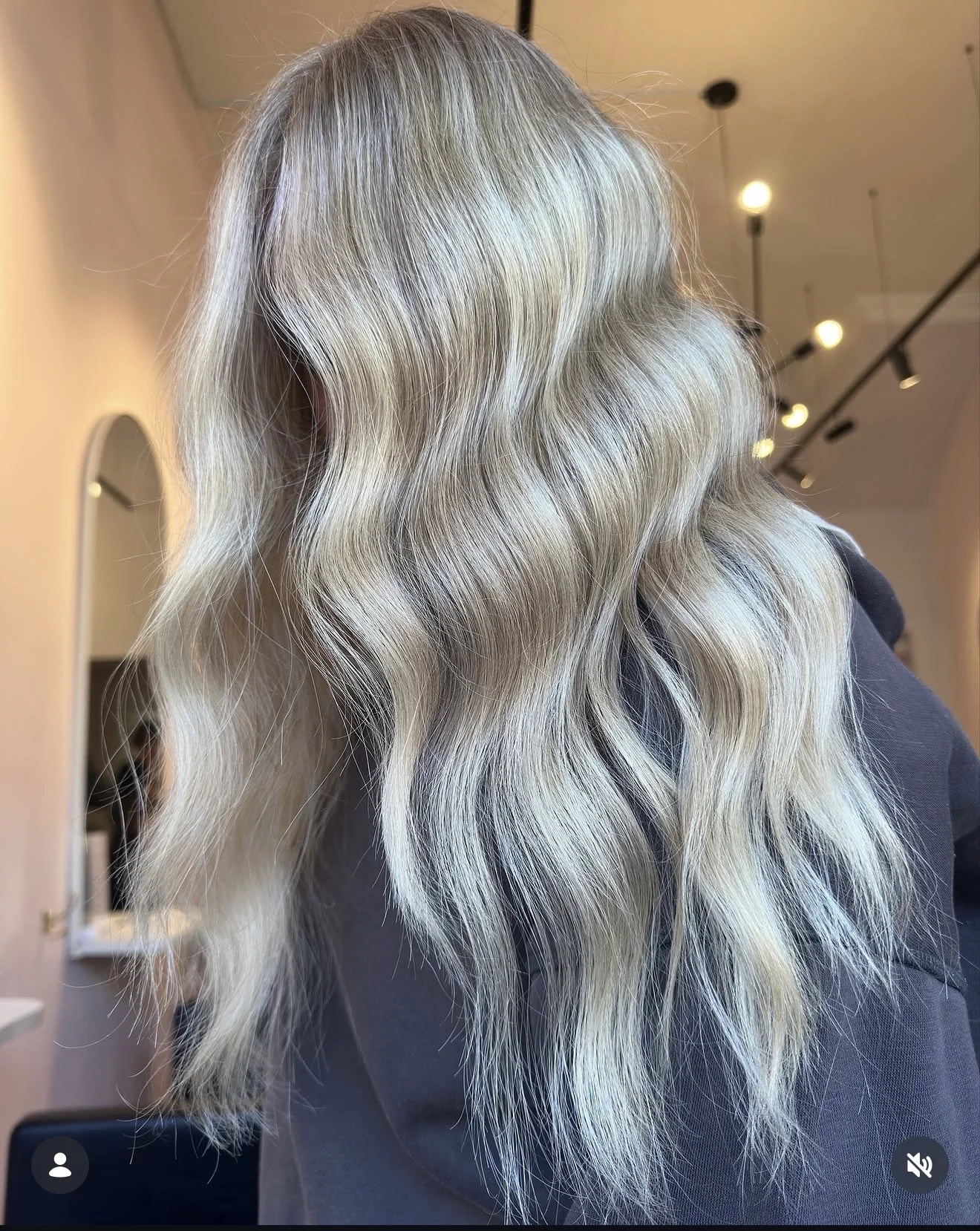 Long, wavy, blonde hair with darker roots, styled in loose waves.