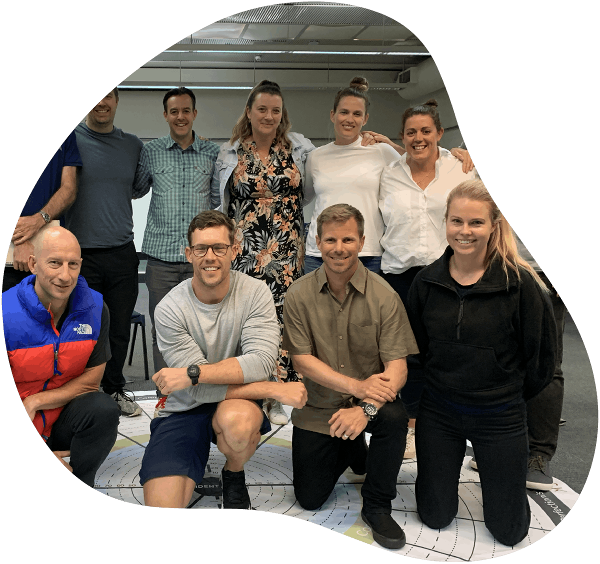 A group of men and women smile at the camera, posing for a group photo during a Nobis group workshop for leadership development.