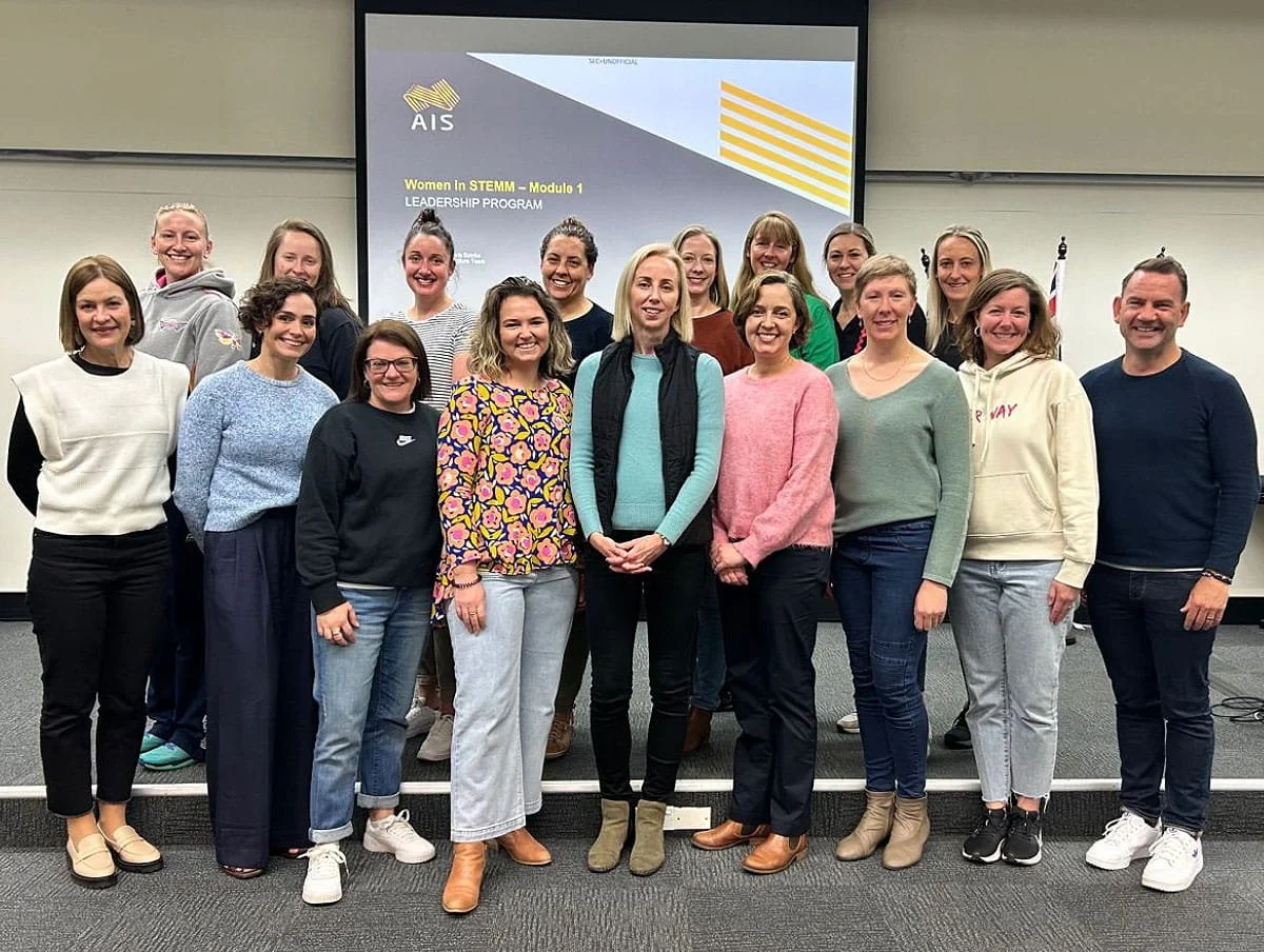 A group of women smile in front of a projector that says 'Women in STEMM Leadership Program' delivered by Nobis