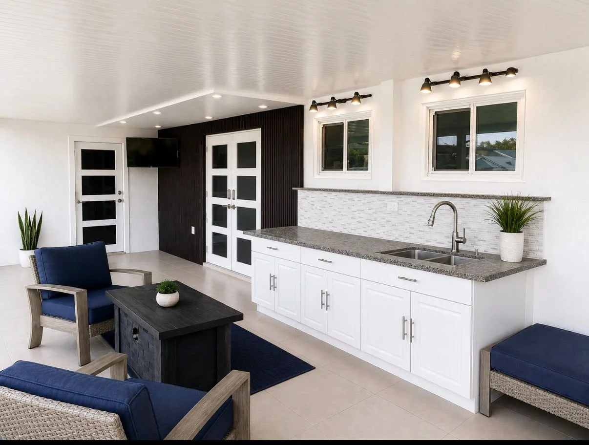 Interior of a modern patio with white cabinets, granite countertops, and a sink, decorated with potted plants and seating area.