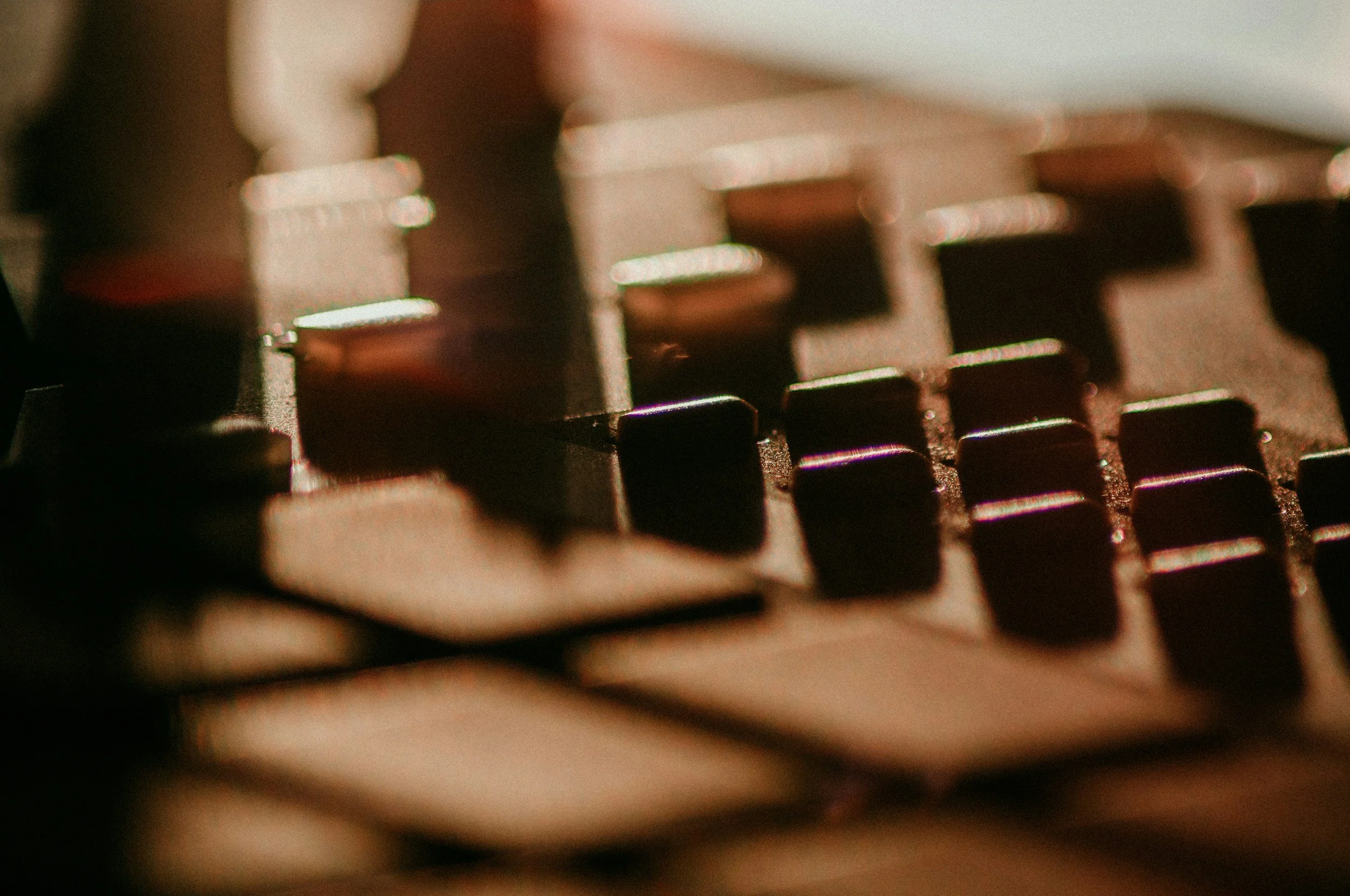 Close-up of a piano keyboard with black and white keys, slightly out of focus with warm lighting.