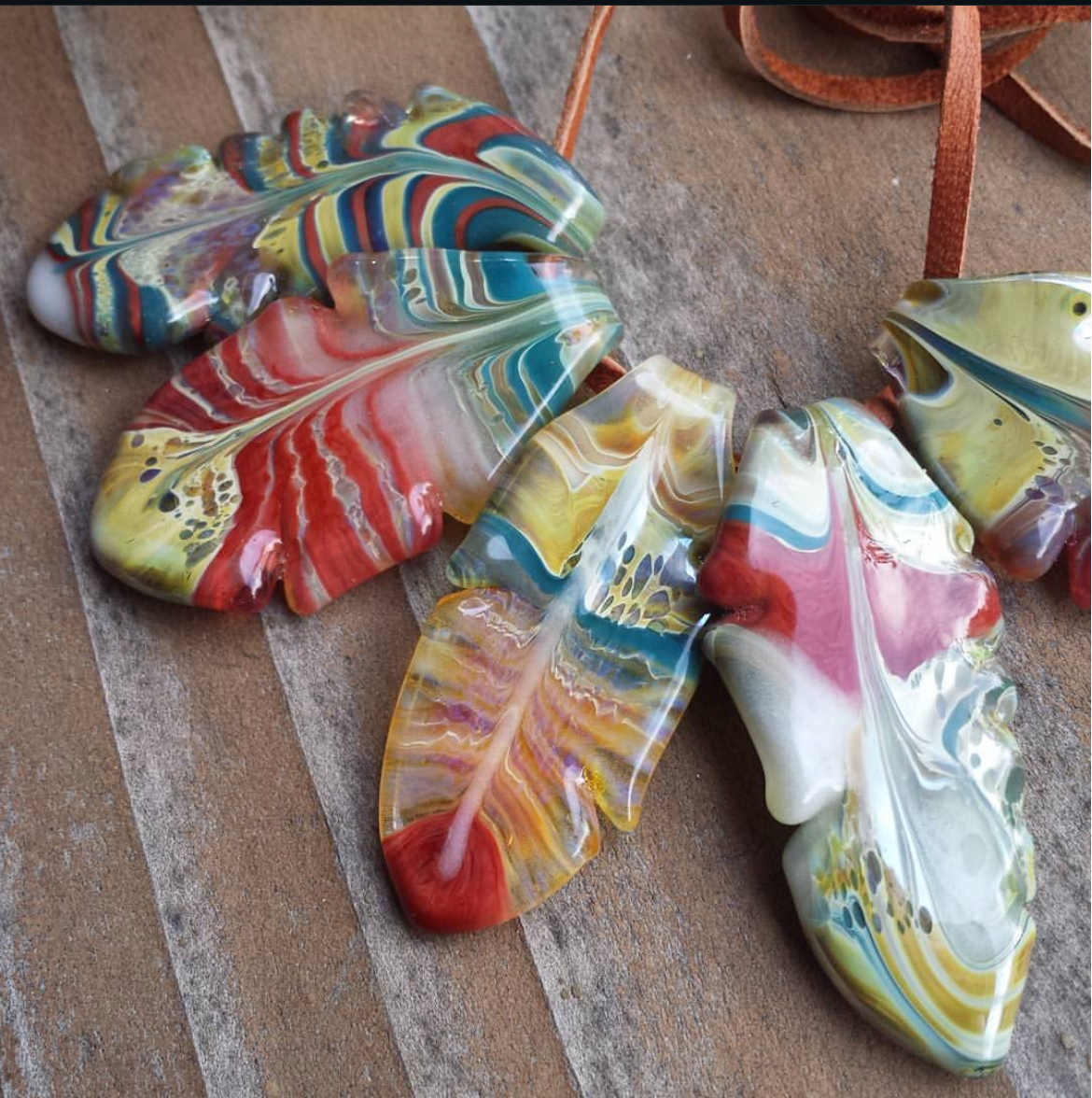 Colorful marbled glass leaf-shaped objects on a wooden surface.
