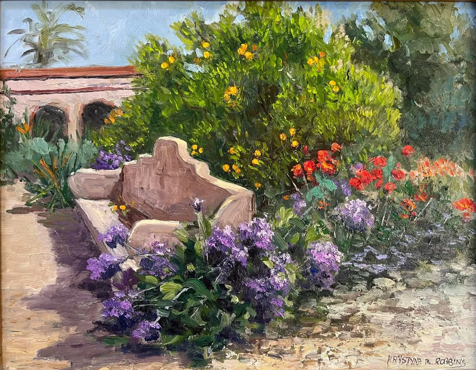 A vibrant impressionist painting of a lush garden with a large green shrub and colorful flowers, including red, purple, and yellow blooms, next to a stone bench and a pink building with arches in the background, under a bright blue sky.