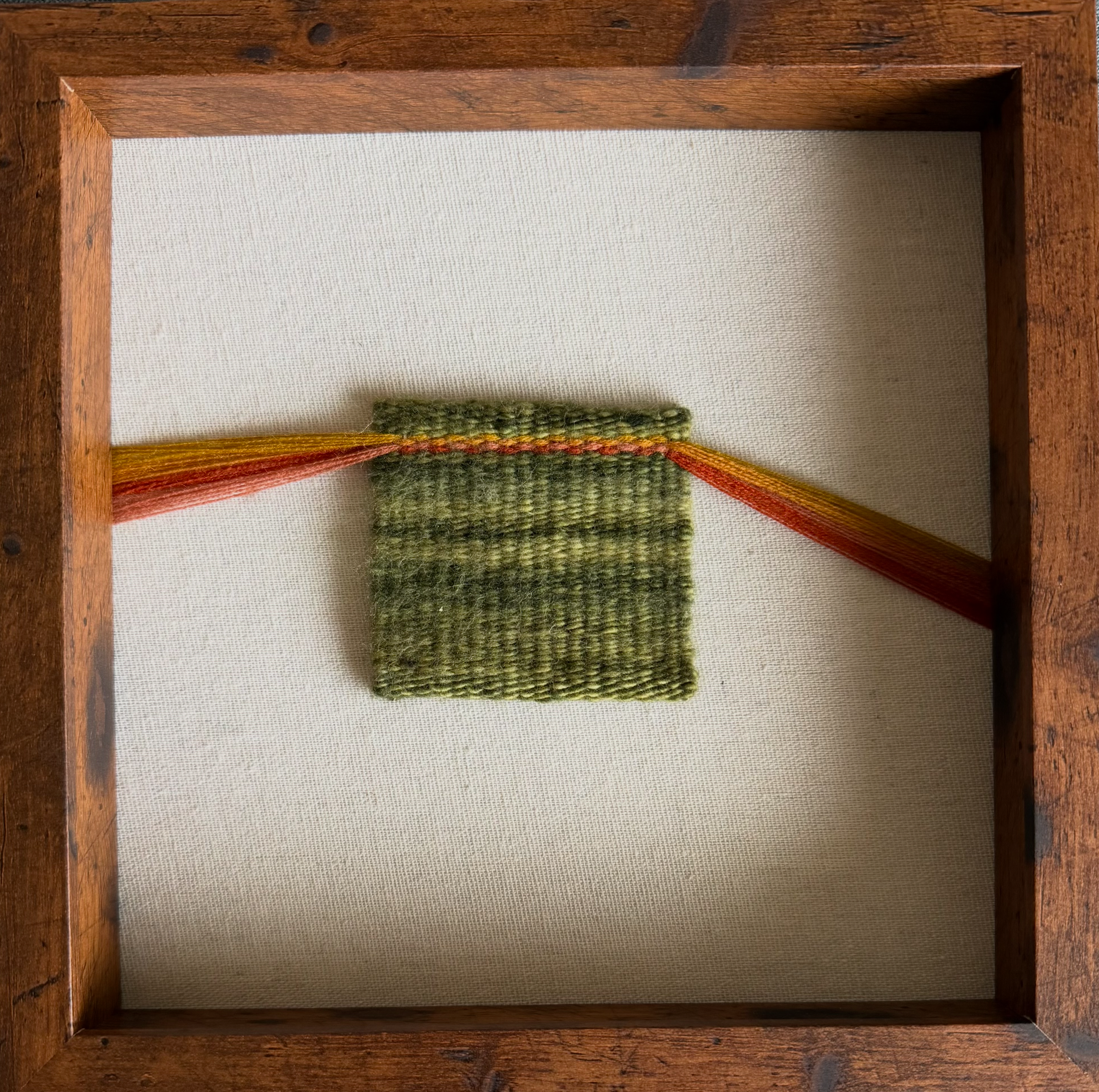 Close-up of a wooden picture frame with a piece of cloth inside.