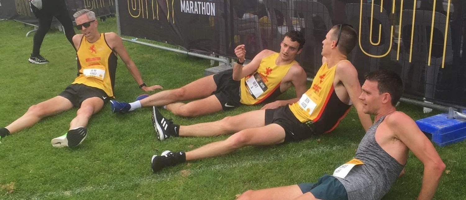 Andrew Wharton and fellow runners resting on the grass after finishing the 2019 Auckland Marathon