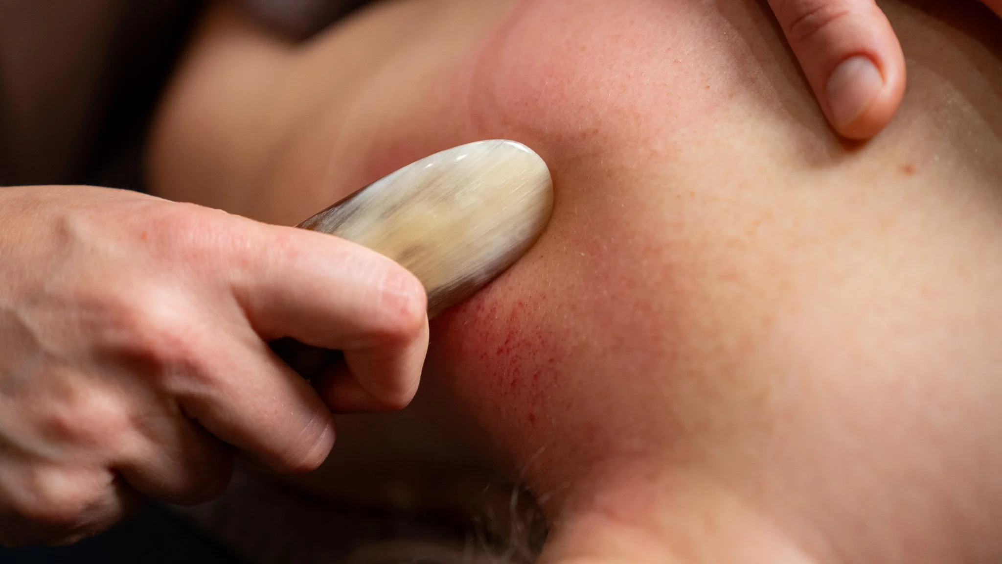 gua sha wollongong Close-up of a massage tool being used on a person's neck.