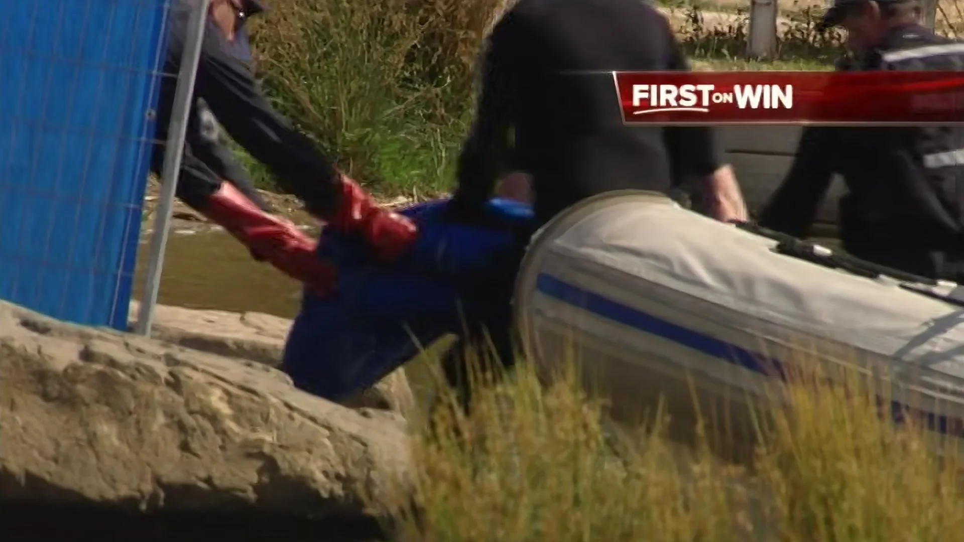 A scene involving emergency responders, with a person being assisted near a blue structure and a boat on the ground. There is a red banner overlay with the text "FIRST ON WIN."
