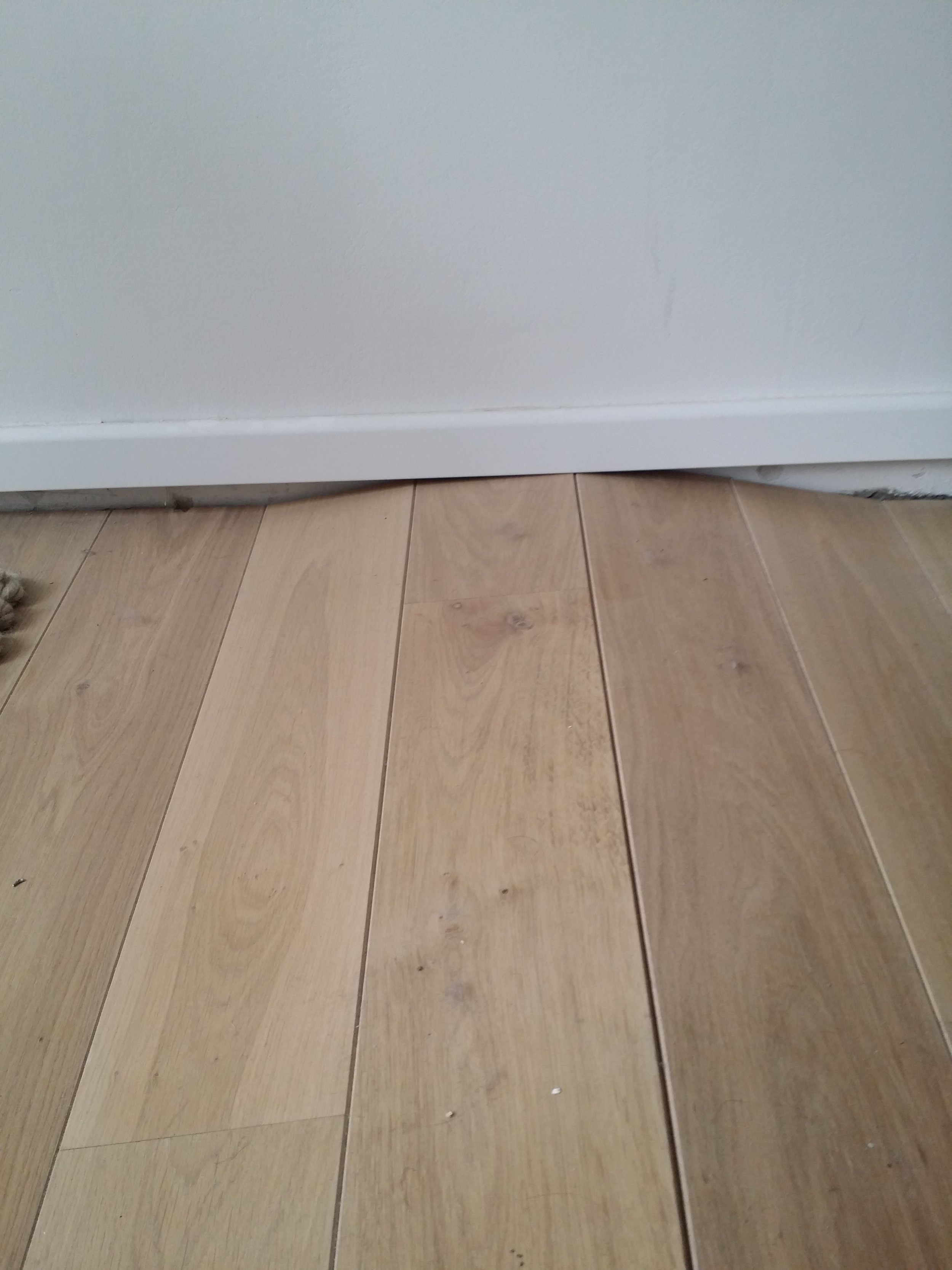 Holzboden mit Zierleiste und weißer Wand