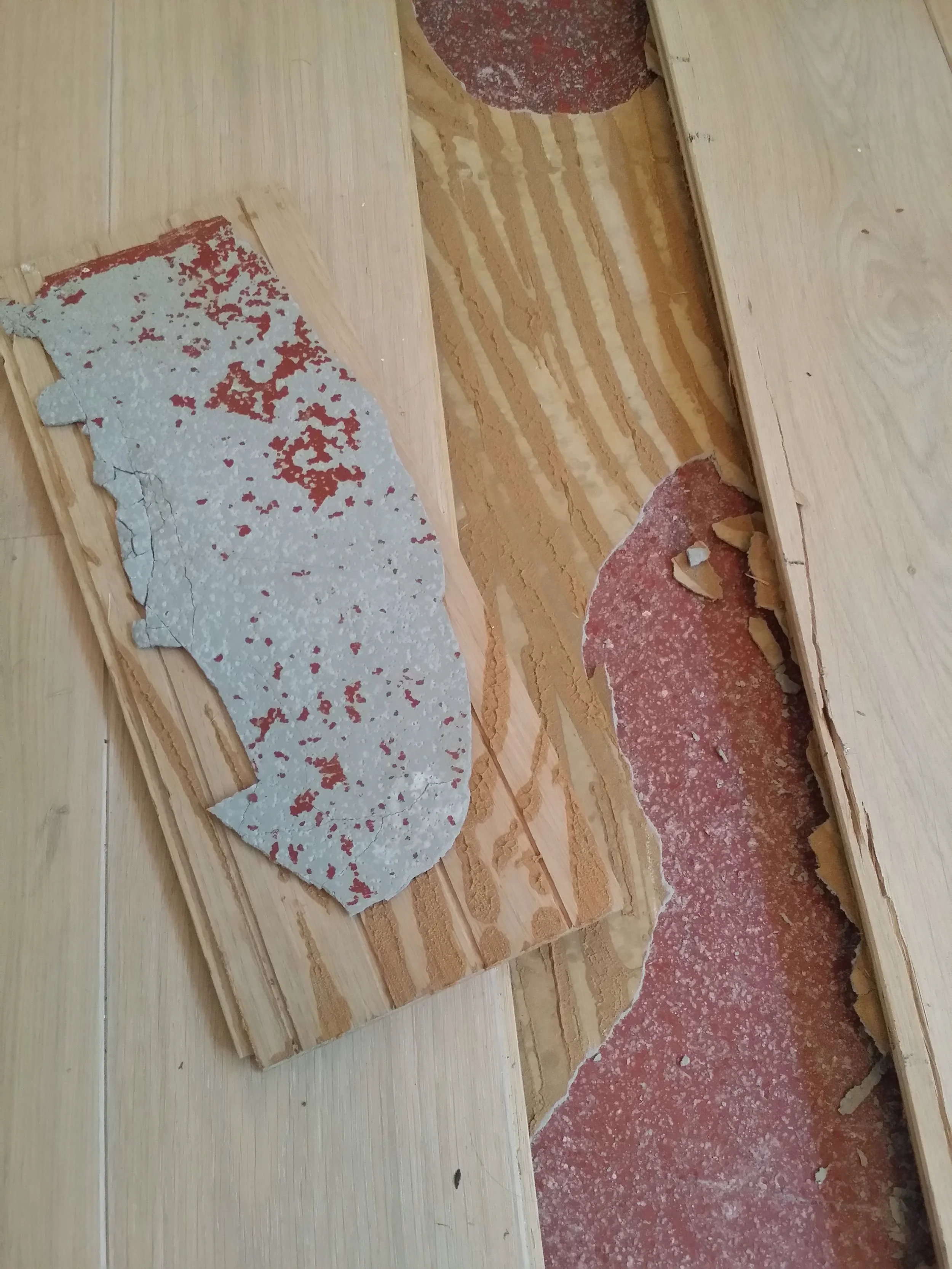 Der Boden im Raum ist teilweise vorbereitet mit Holzplatten und Estrich, während andere Bereiche noch unvollständig sind, mit sichtbarem rotem Estrich und Bauabfällen.