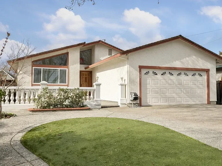 Front view of a two-story house with a white exterior, brown accents, a garage, and a small front yard.
