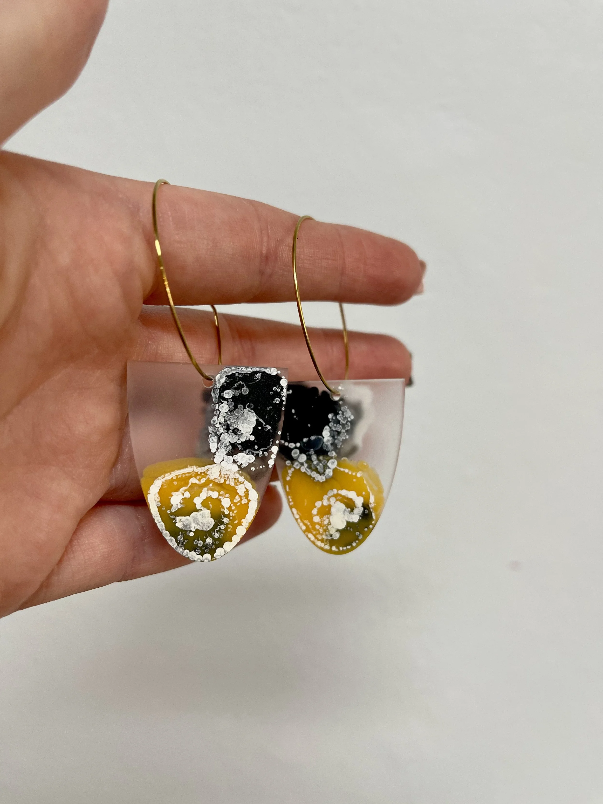 Image of black and yellow dangle earrings made with clear resin  on gold hoops