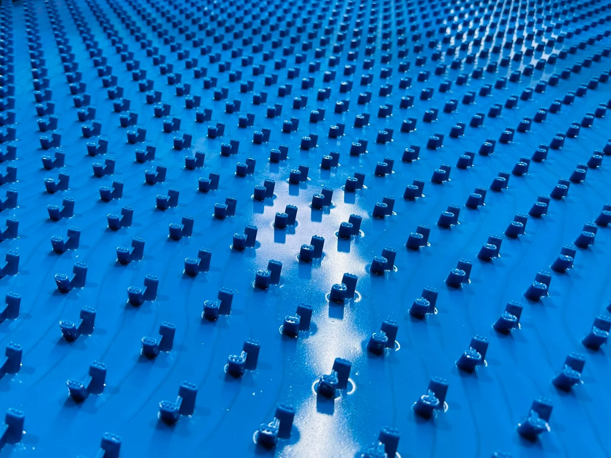 Close-up of blue HDPE liner sheet showing its anchor knobs