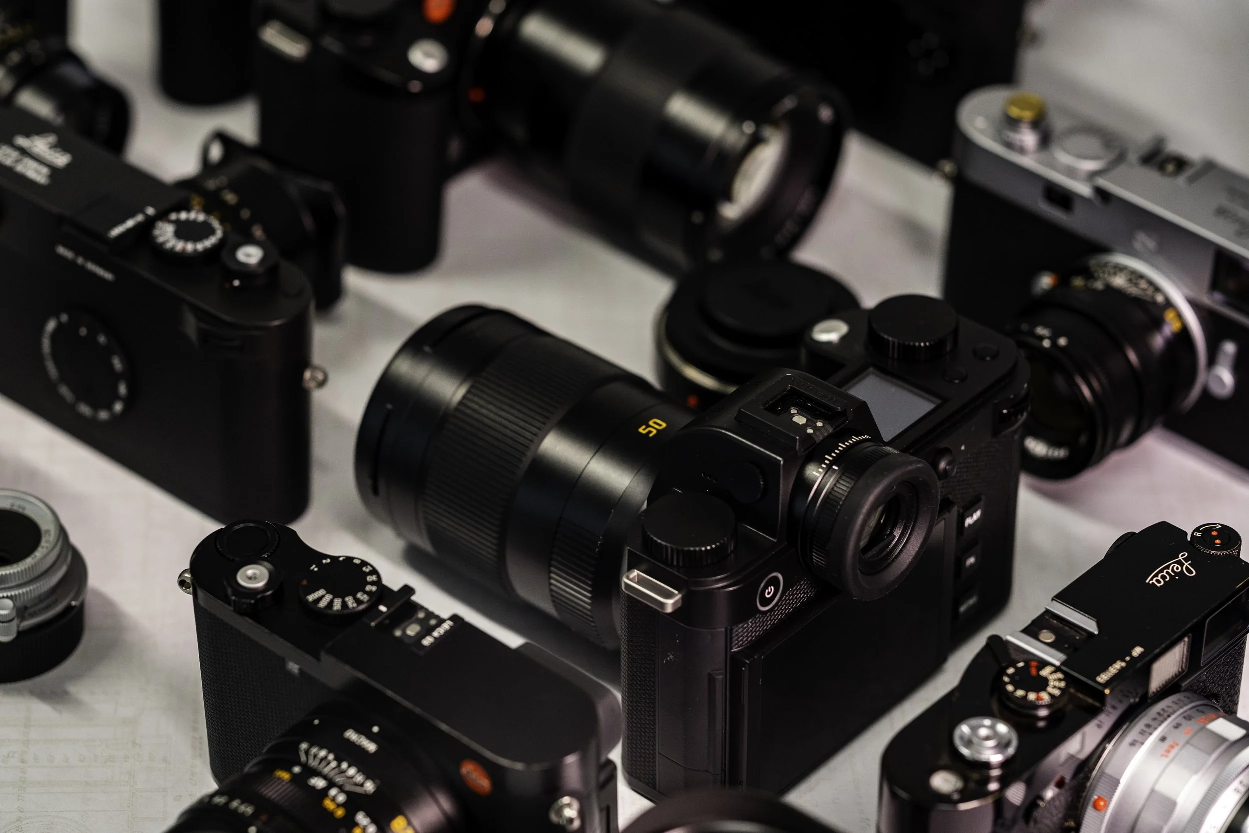 Multiple cameras and camera lenses displayed on a table.
