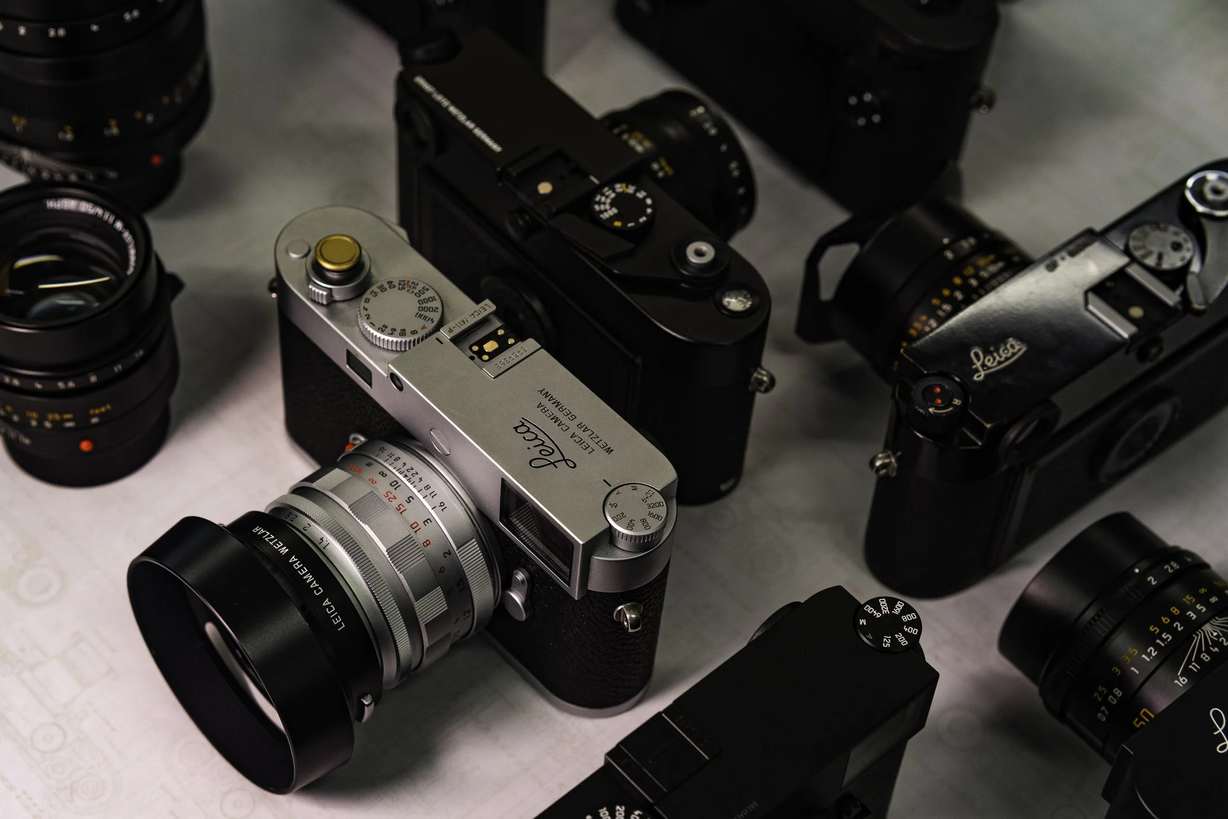 A collection of vintage cameras with various lens sizes and styles, arranged closely together on a flat surface.