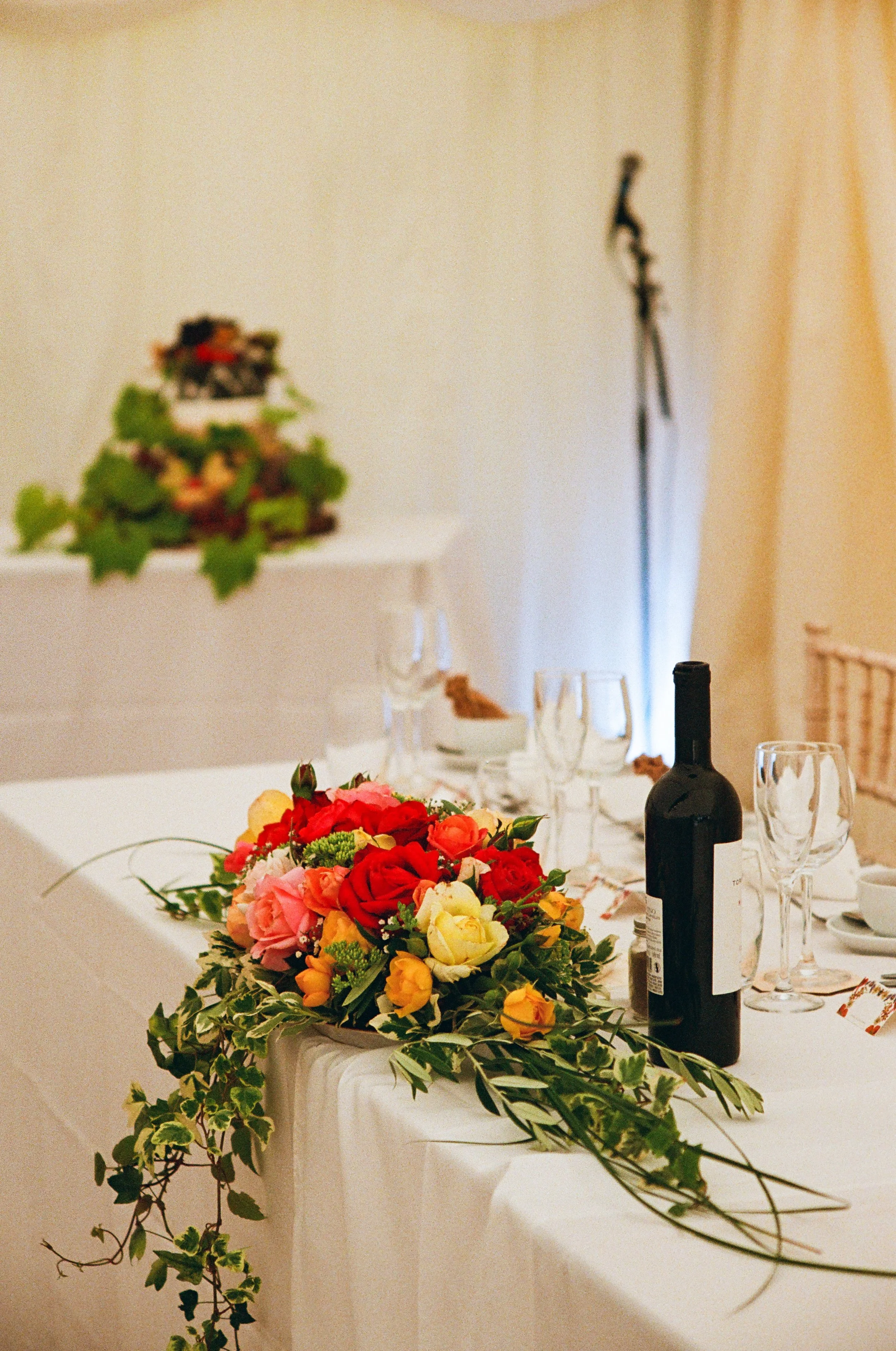 A table decorated with a colorful bouquet of flowers and wine bottles, set for a celebration or dinner event.
