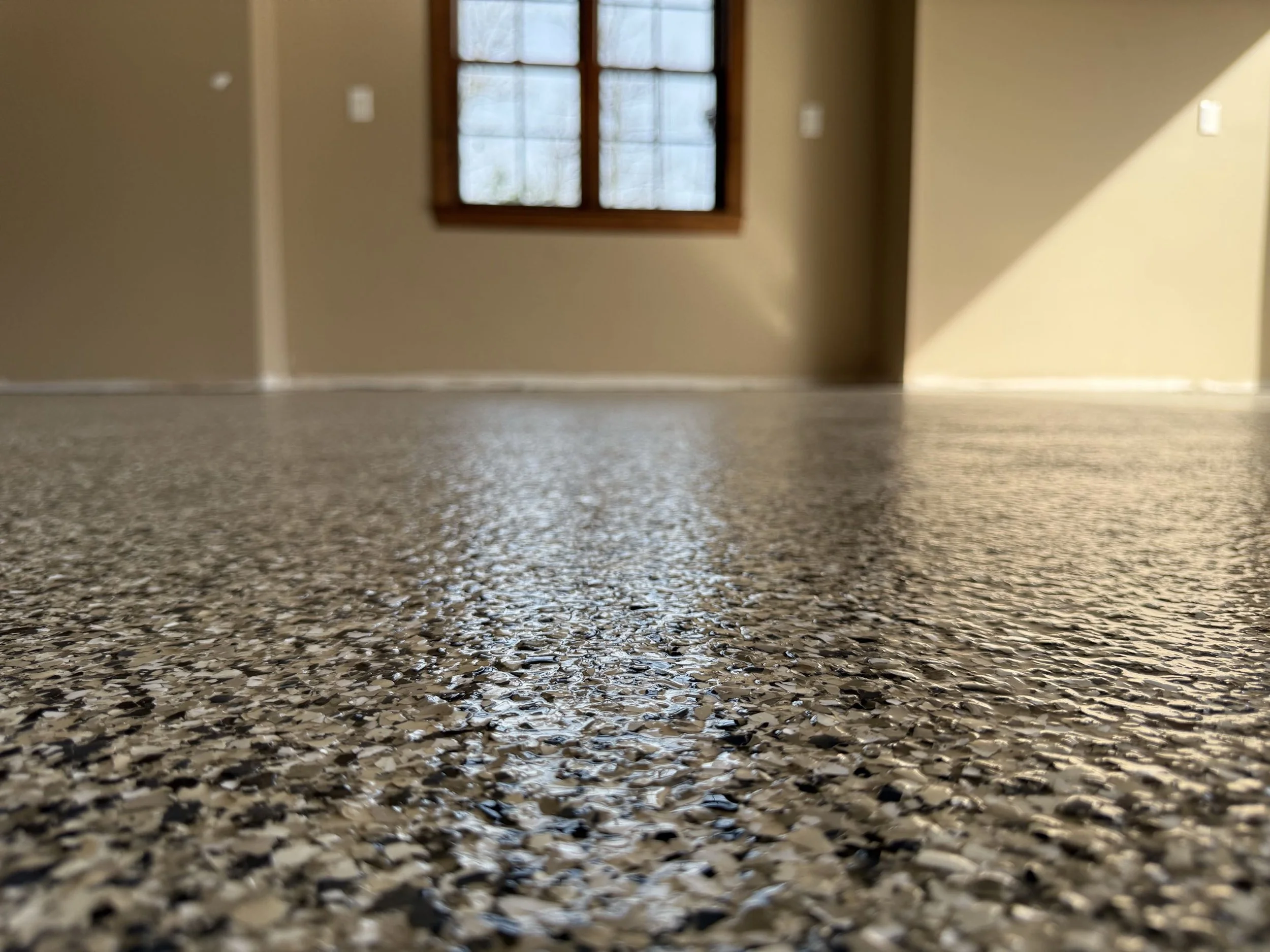 Close-up of a textured speckled countertop with a window in the background allowing natural light to fill the room.