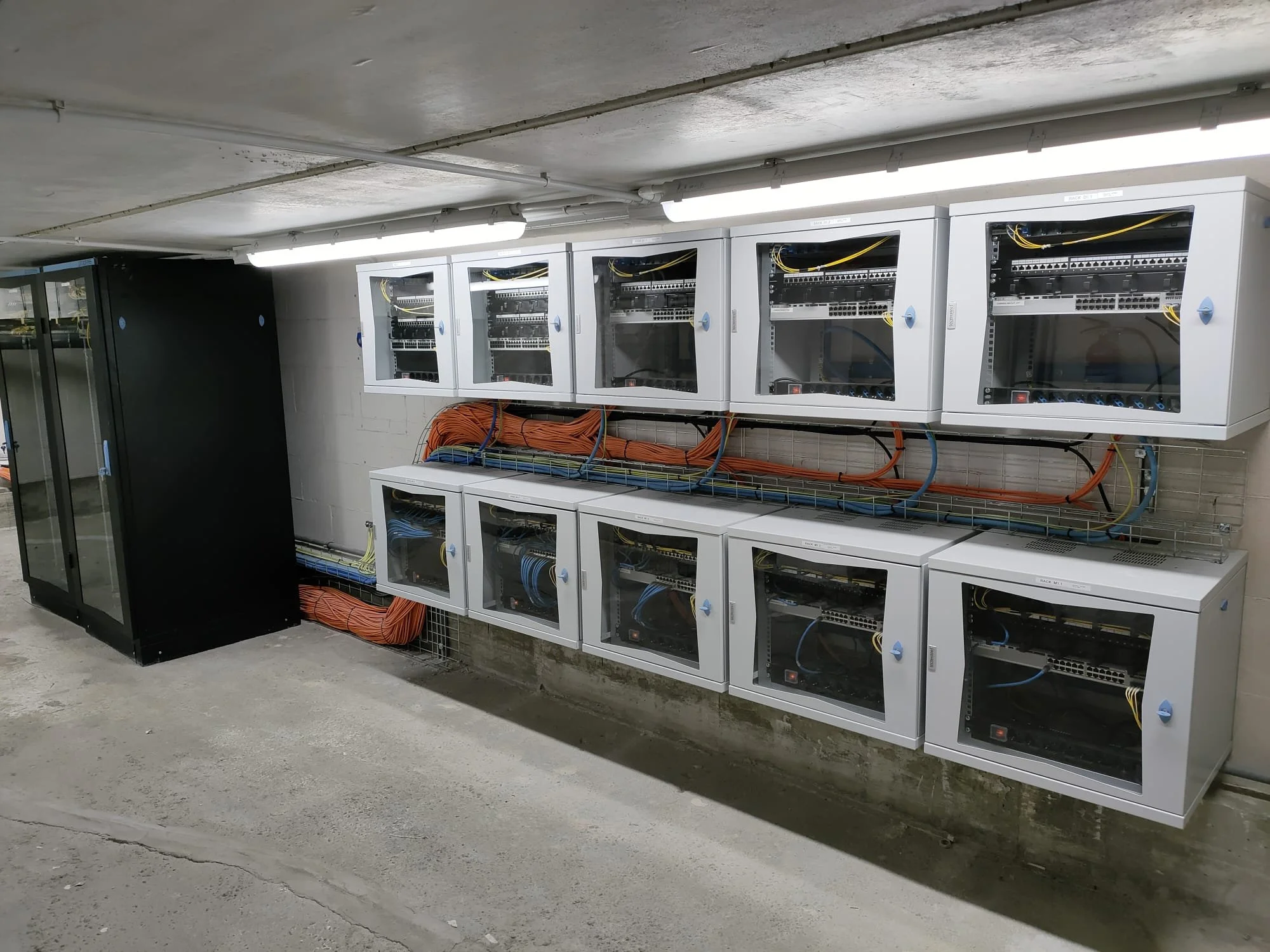 Armadi rack per server con cavi di rete e cablaggio, situati in un ambiente industriale o server room.