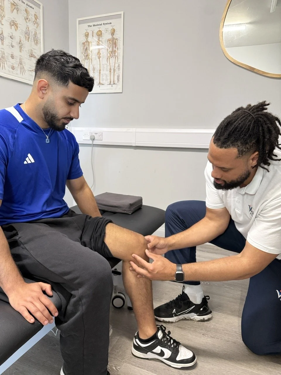 Physiotherapist assessing a mans knee with his hands