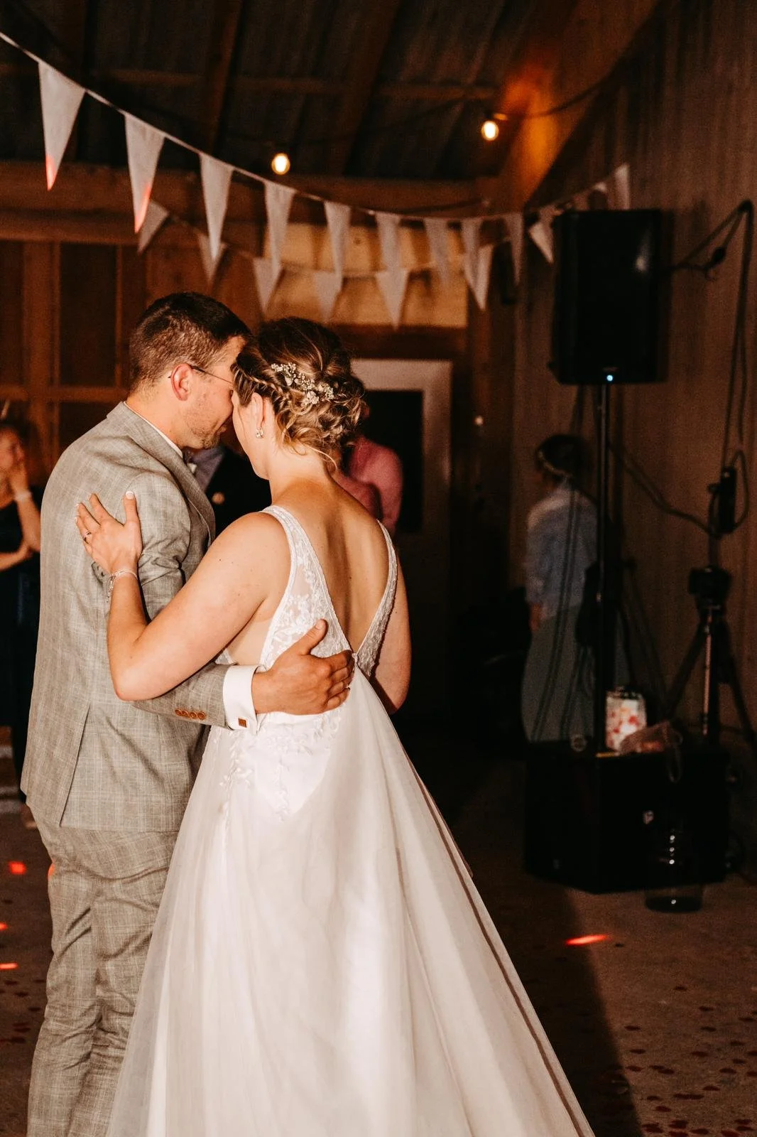 Ein Paar tanzt bei einer Hochzeit in einem rustikalen, holzvertäfelten Raum, mit weißen Partydekorationen im Hintergrund.