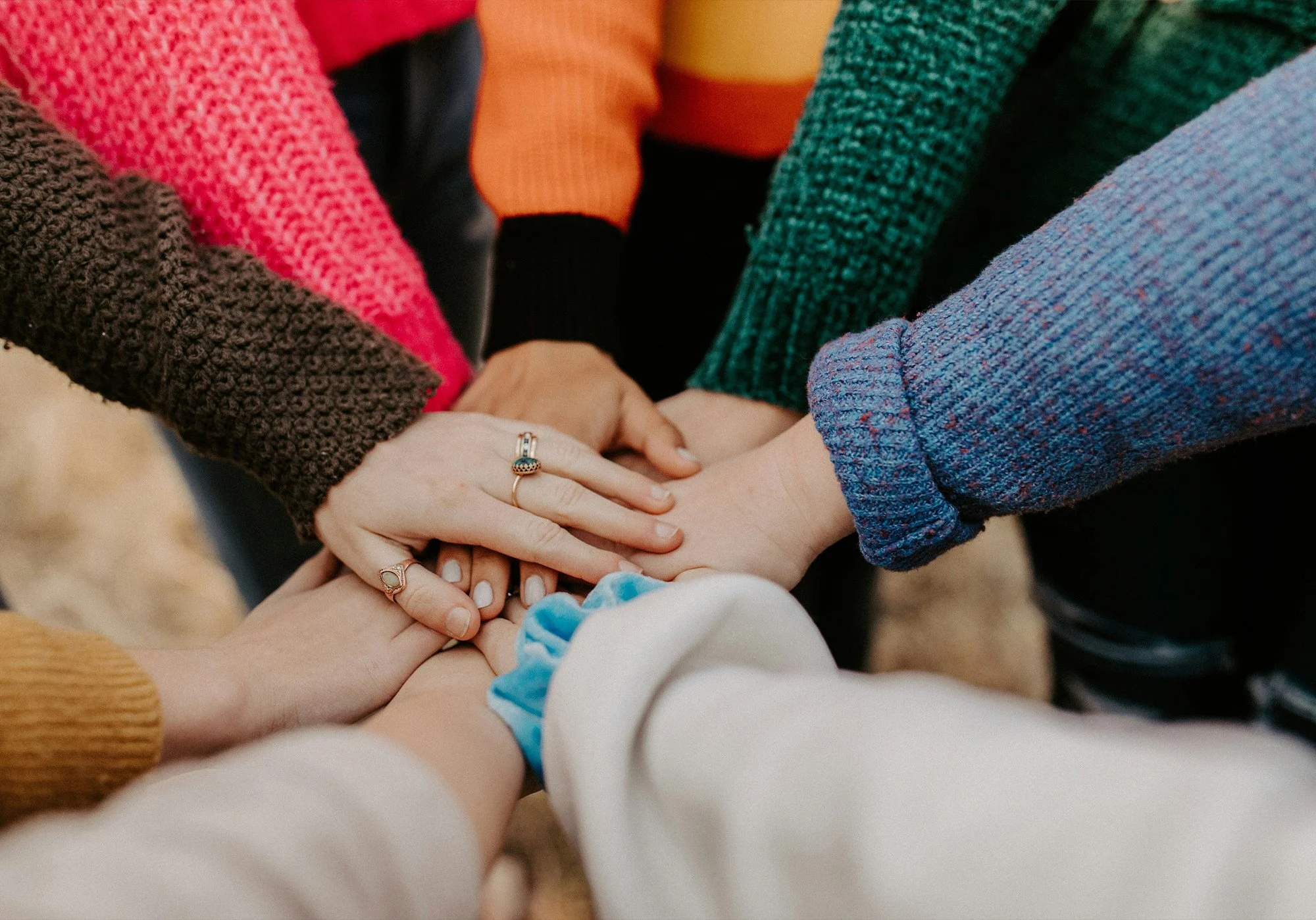 Diverse group placing hands together symbolizing inclusion, teamwork, and innovation
