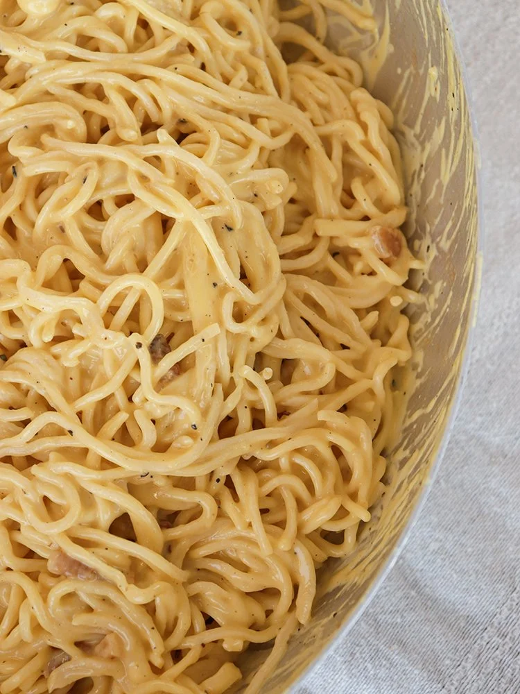 Creamy prepared ramen noodles in a container, with a slightly yellowish sauce.