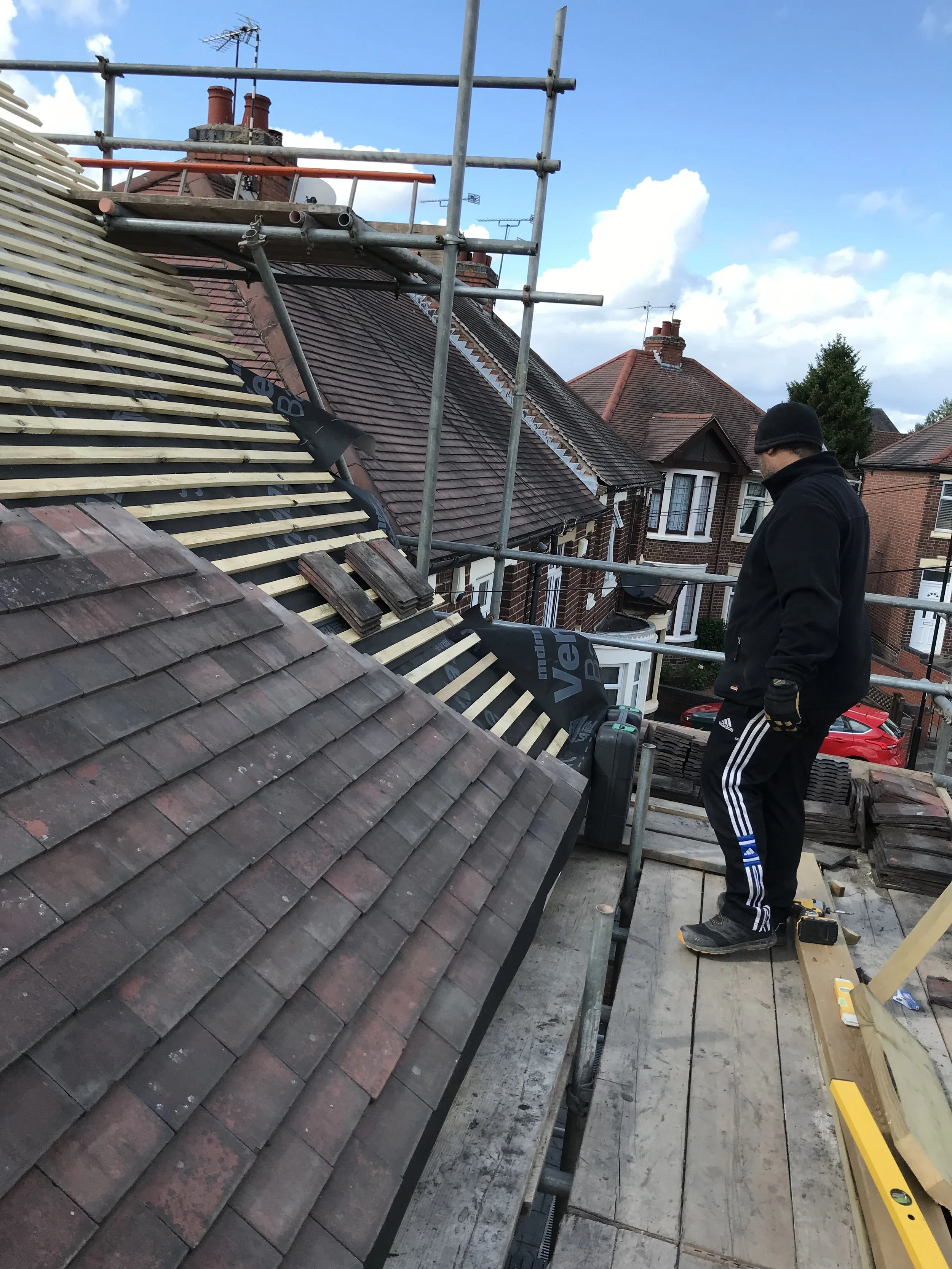 Radian Roofing installer fitting roof tiles on a pitched roof on a brick terraced property in Birmingham and Solihull
