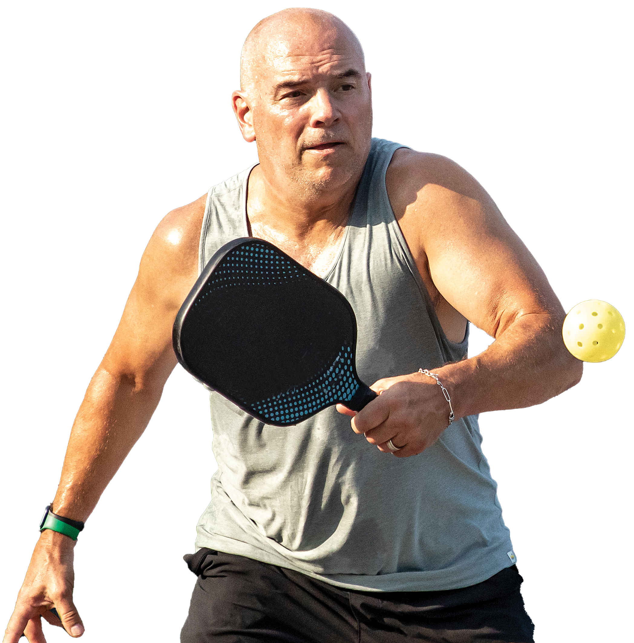 A male pickleball player in a sleeveless gray shirt preparing to hit a pickleball with a racket, wearing a black wristband with a green bar on his hand, against a colorful background.