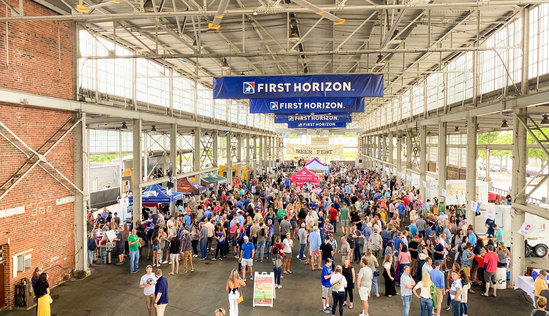 Crowd attending the Chattanooga Beer Fest in a large indoor venue with metal beams and banners for First Horizon.