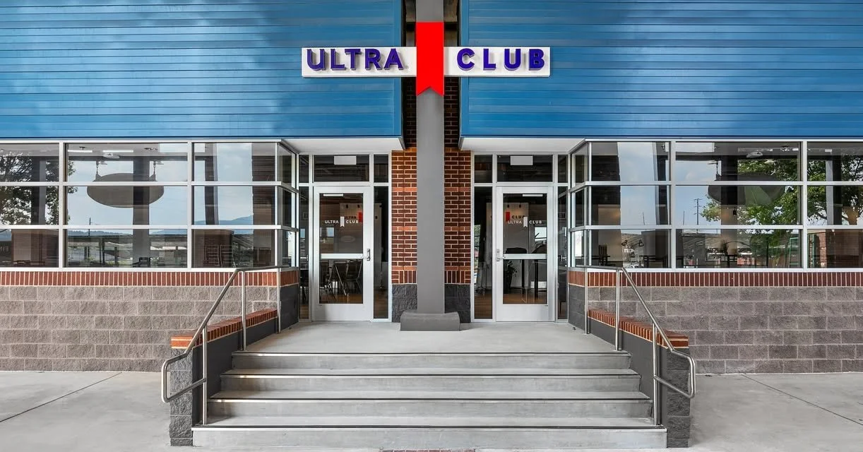 Exterior of Ultra Club building with glass doors, brick and blue paneling, stairs, and signage.