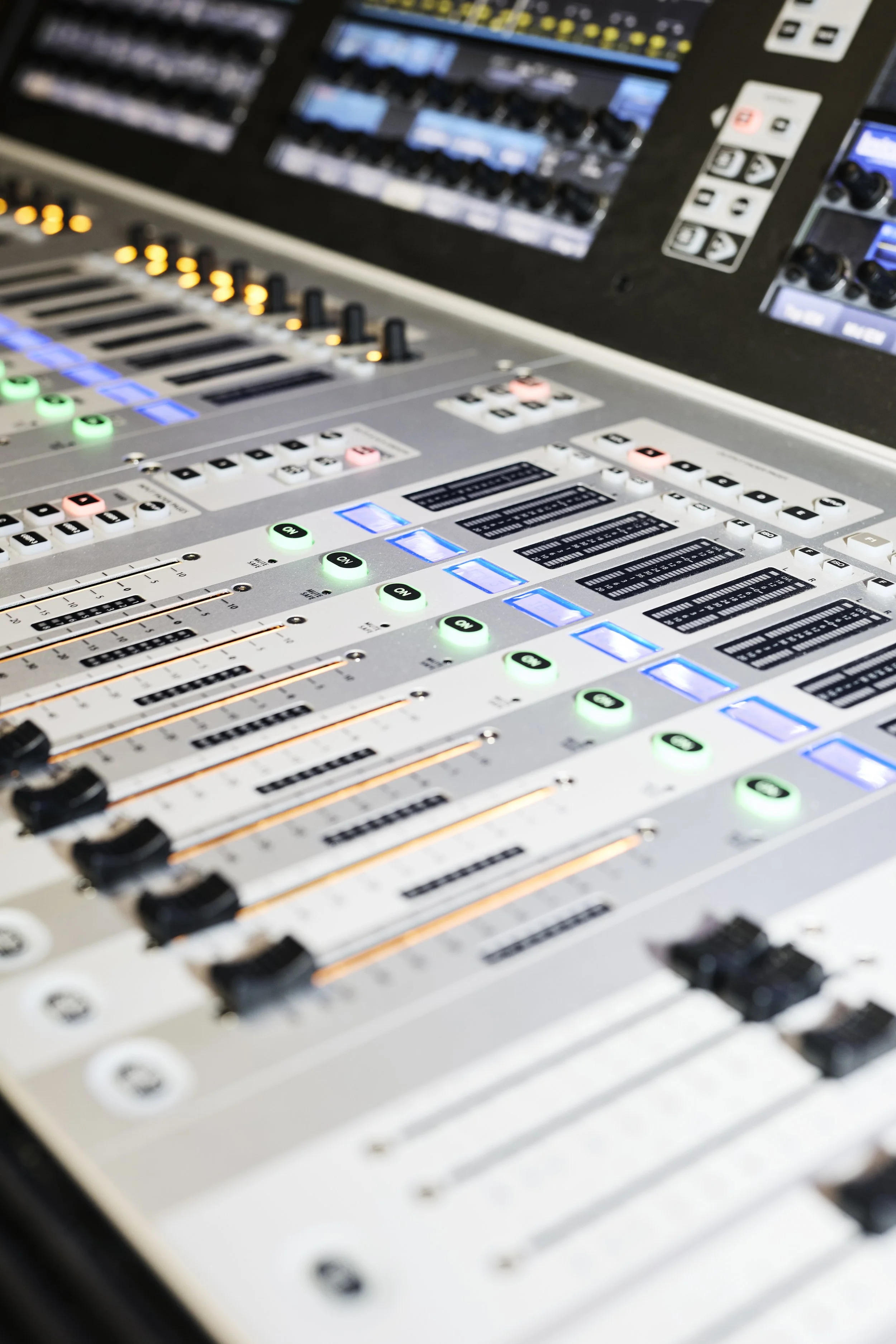 A professional audio mixing console with illuminated buttons, knobs, and sliders, used for sound engineering and music production.