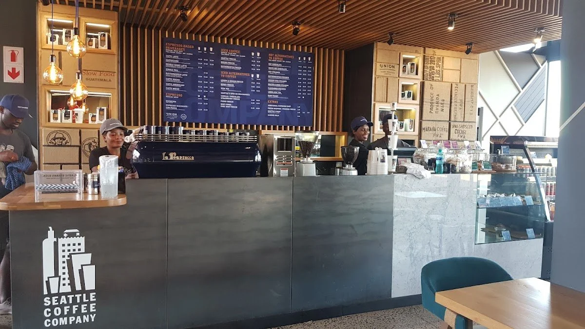 Interior of Seattle Coffee Company with a counter, baristas, and a menu board.