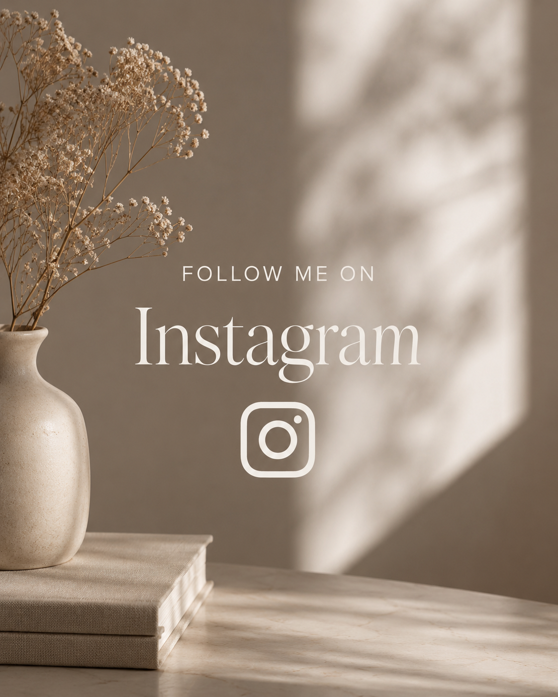 A beige vase with dried white flowers on a stack of two beige books on a marble table with a shadowy background. Text overlay reads 'Follow me on Instagram' with the Instagram logo.