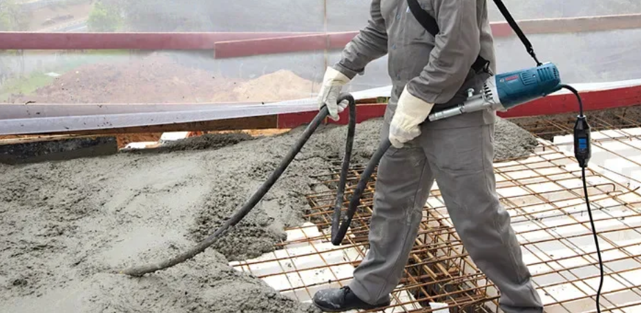 Çalışan, inşaatta beton dökerek zemini düzleştiriyor.