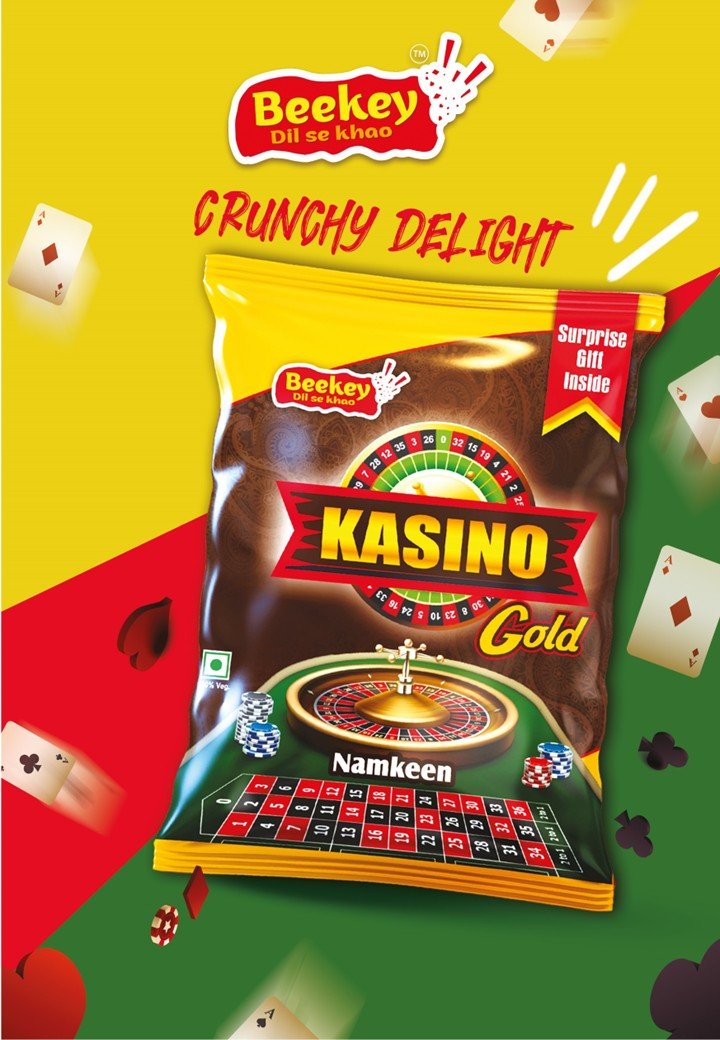 The image features a package of Beekey Kasino Gold snack chips with the tagline 'Crunchy Delight'. The package highlights a surprise gift inside. The background is divided into yellow, red, and green sections, decorated with playing cards and poker c