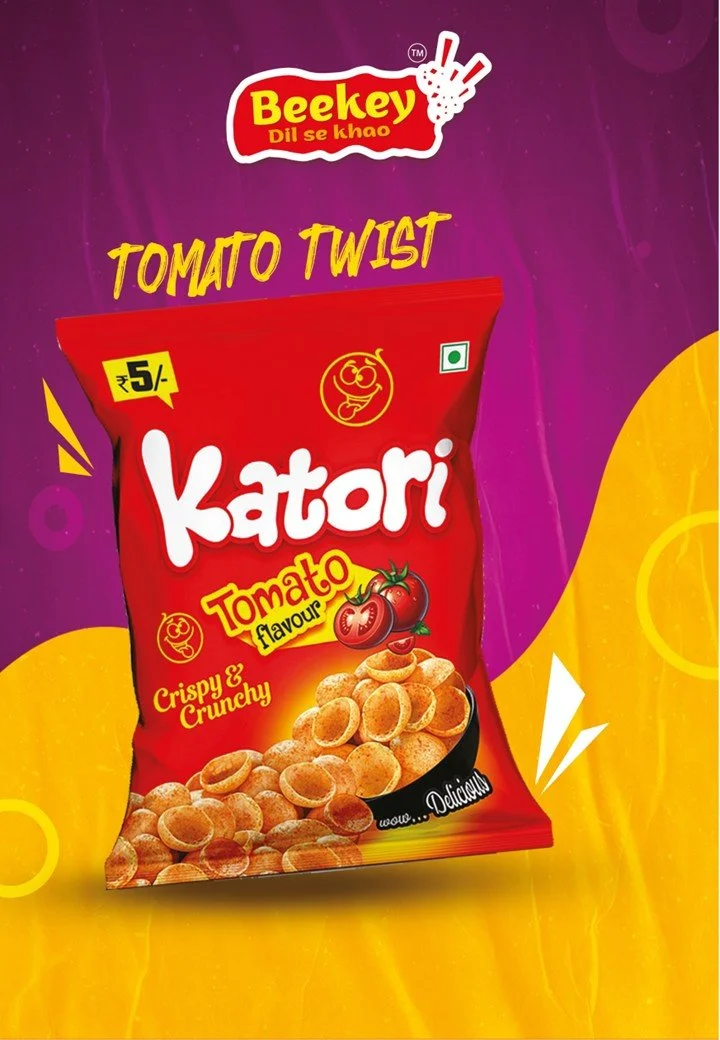 A red bag of Katori Tomato Twist snack, with image of crunchy tomato-flavored chips and tomatoes on packaging, and purple and yellow background.