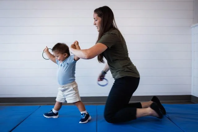 Jordan Greiner assisting a pediatric patient to walk with Down Syndrome