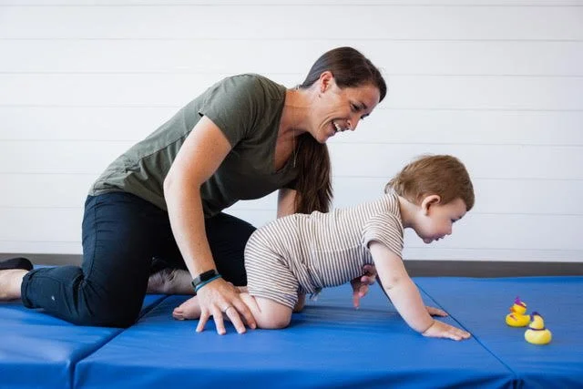 Jordan Greiner, DPT assisting a boy with a genetic disorder to get into hands and knees and functional positions and crawl
