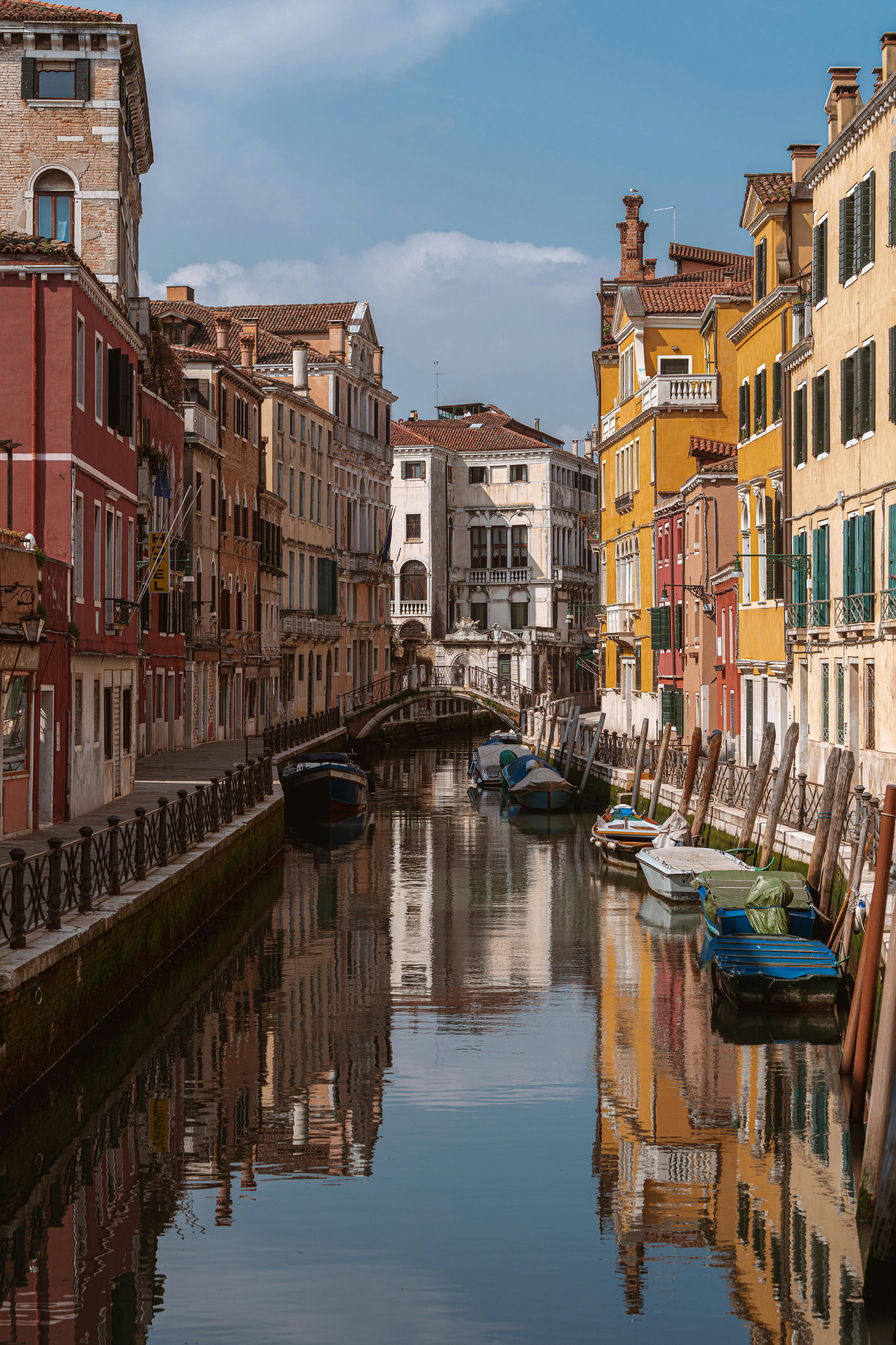Colorful buildings along a narrow canal with small boats docked, typical of Venice, Italy.