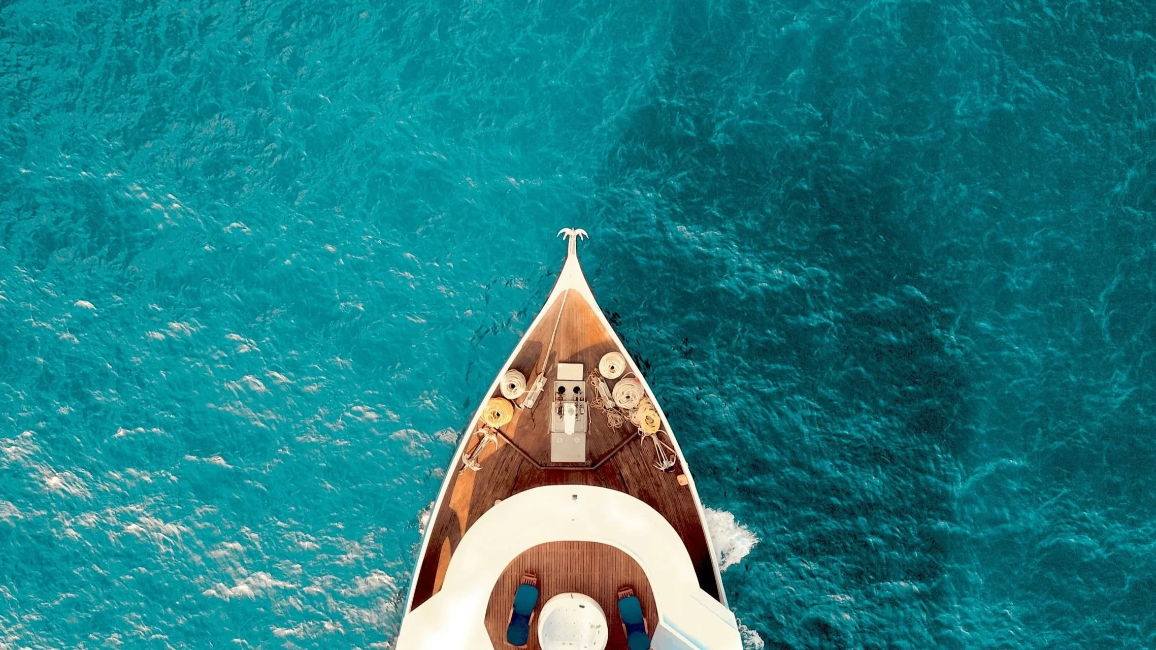 Aerial view of a ship at sea in Zanzibar, with the front of the ship visible, showing the deck and ropes, as the ship moves through the water.