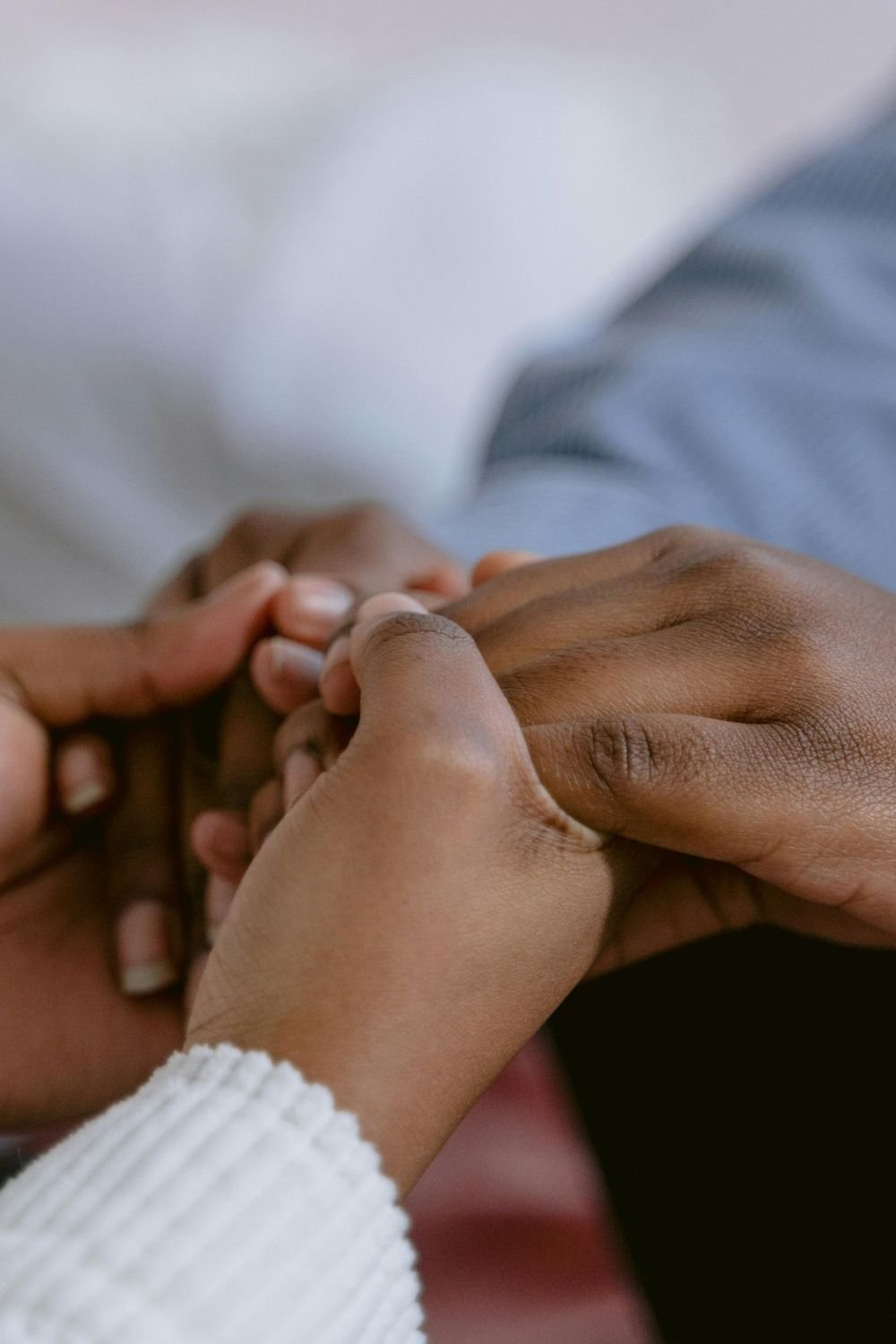 Close-up of two people holding hands in a comforting gesture, symbolizing emotional support, connection, and mental health guidance during challenging times.