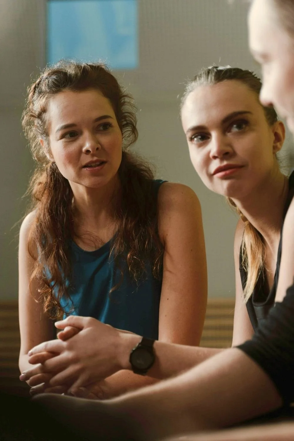 Two women engaged in a thoughtful discussion during a support group or wellness session, sharing experiences and encouragement in a safe, supportive environment.