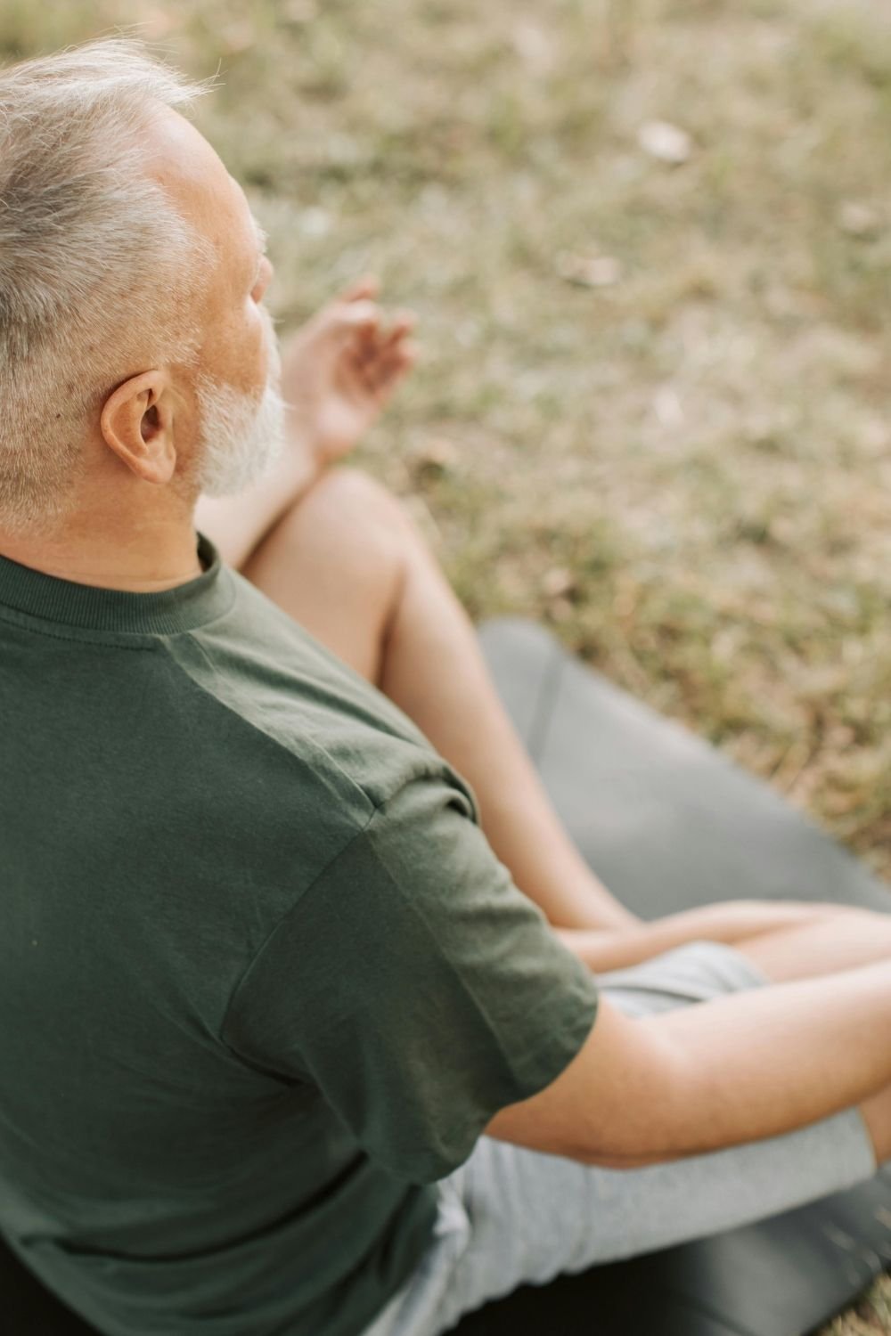 An older adult seated outdoors in a peaceful meditation pose on a yoga mat, promoting mindfulness, balance, and mental health and emotional wellbeing through intentional self-care practices.