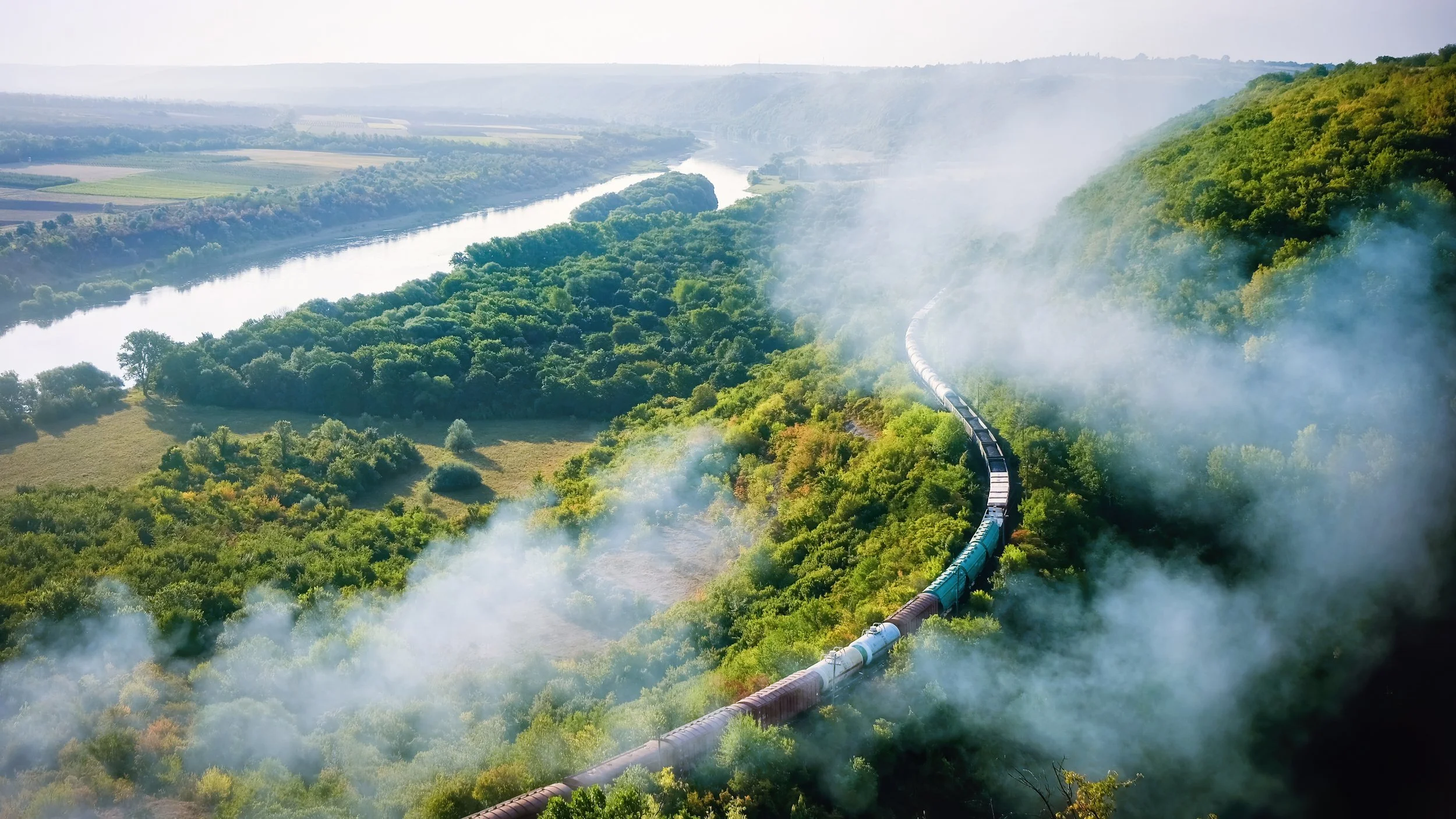moving-train-railway-with-high-column-smoke-flowing-river-hills-railway-foreground.jpg