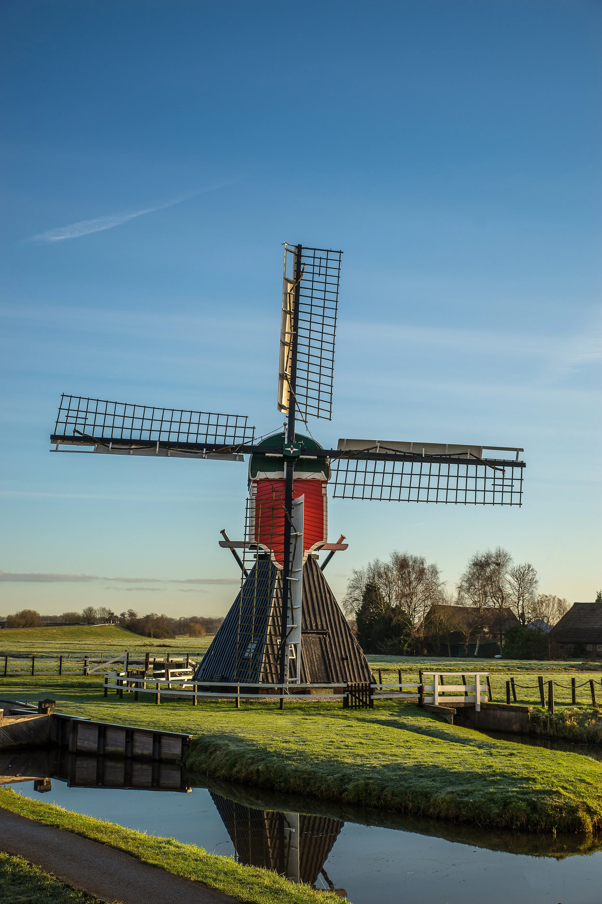 vertical-shot-post-mill-grassy-field-with-wooden-fences-blue-sky.jpg