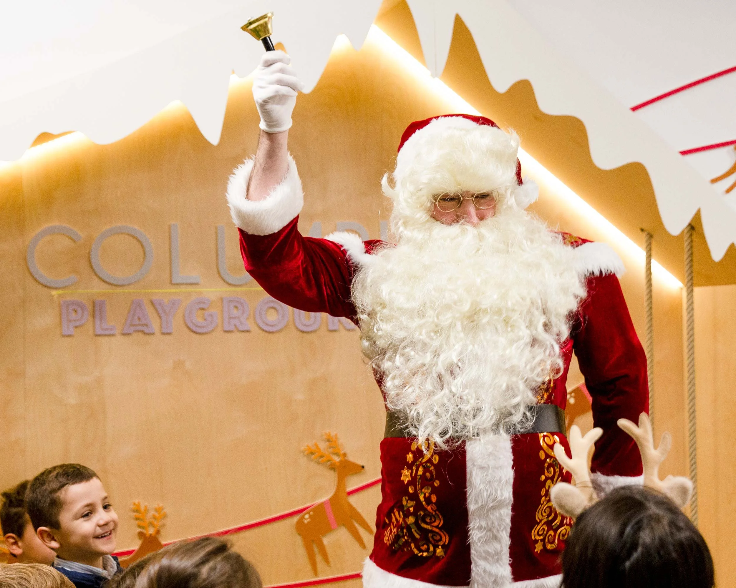 Papá Noel saludando a niños en una fiesta navideña en Columpio Playground, espacio infantil para eventos de temporada en Madrid.