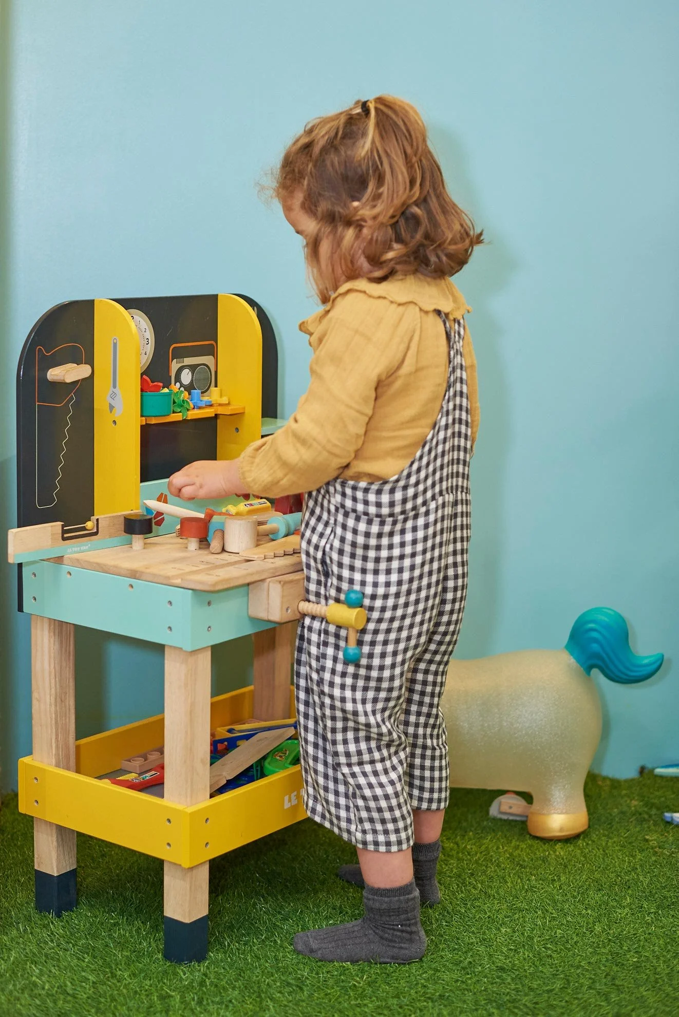 Niño jugando en una mesa de madera con juguetes de colores en Columpio Playground, espacio infantil familiar en Madrid.