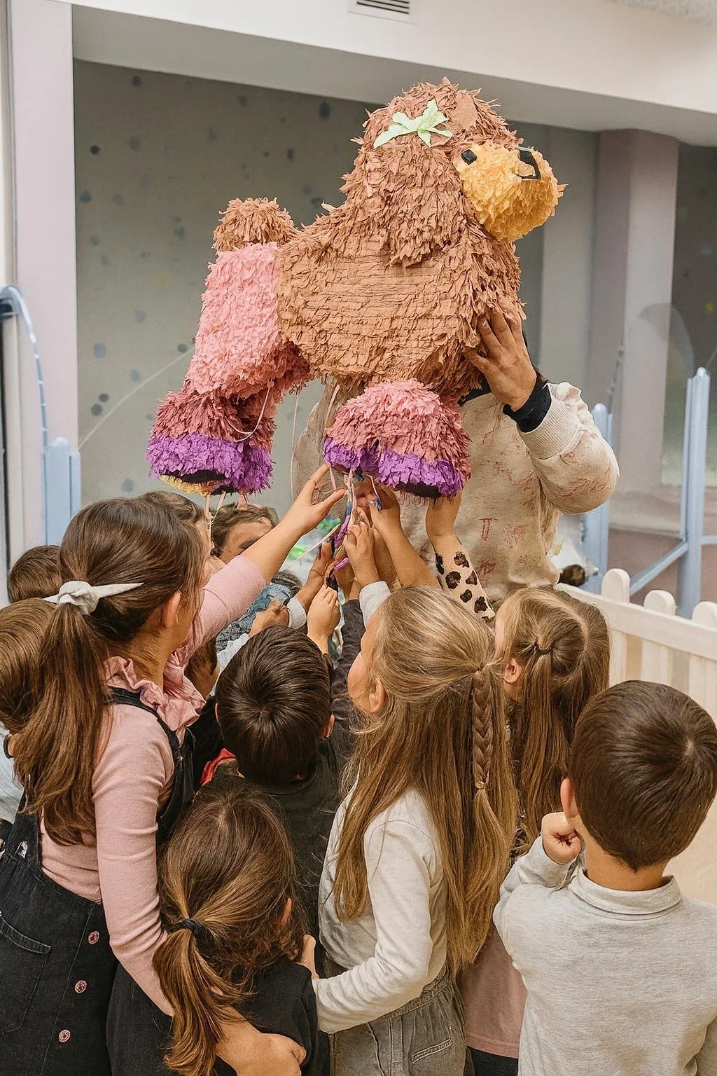 Niños en un cumpleaños infantil en Columpio Playground Madrid tocando una piñata con forma de león